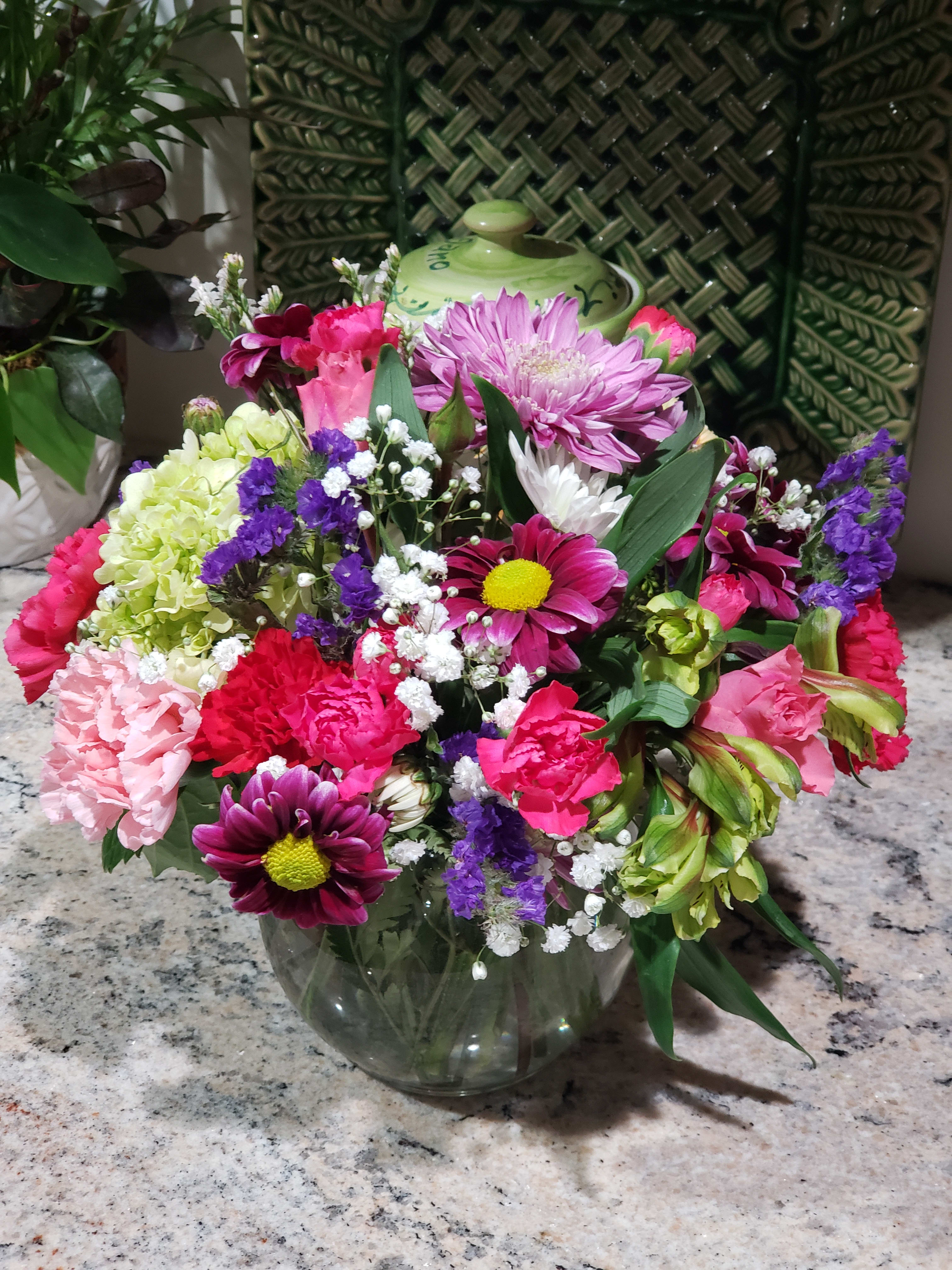 Mixed bouquet in a clear glass vase with pink, purple, white, and green flowers