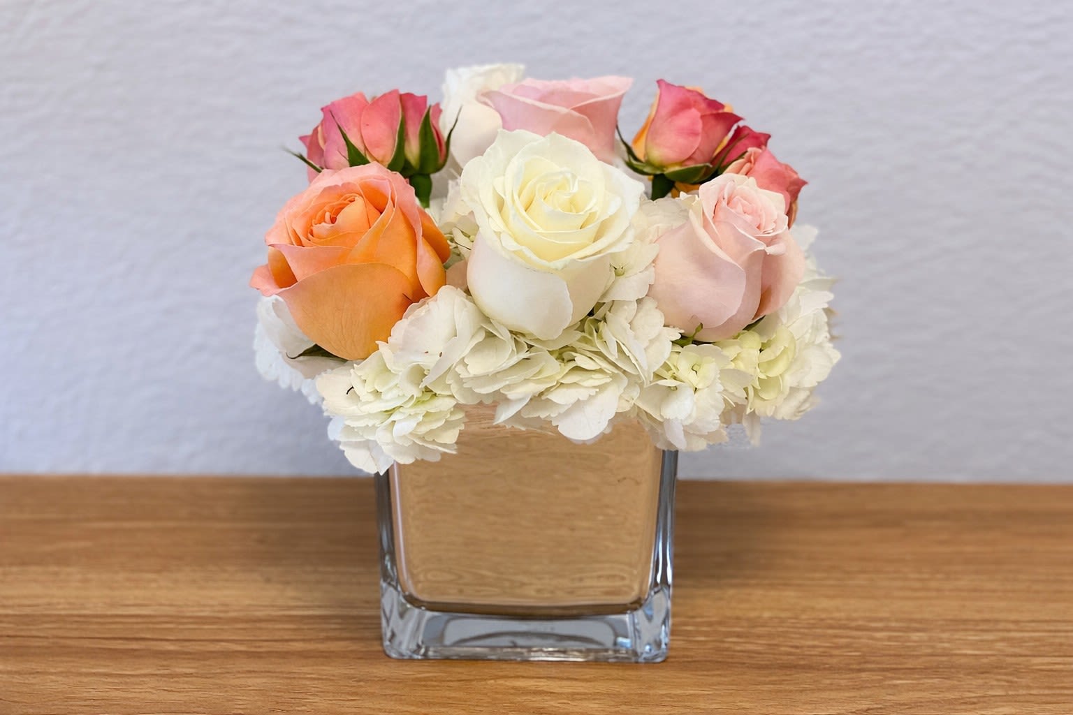 Mixed roses and white hydrangeas in a square glass vase