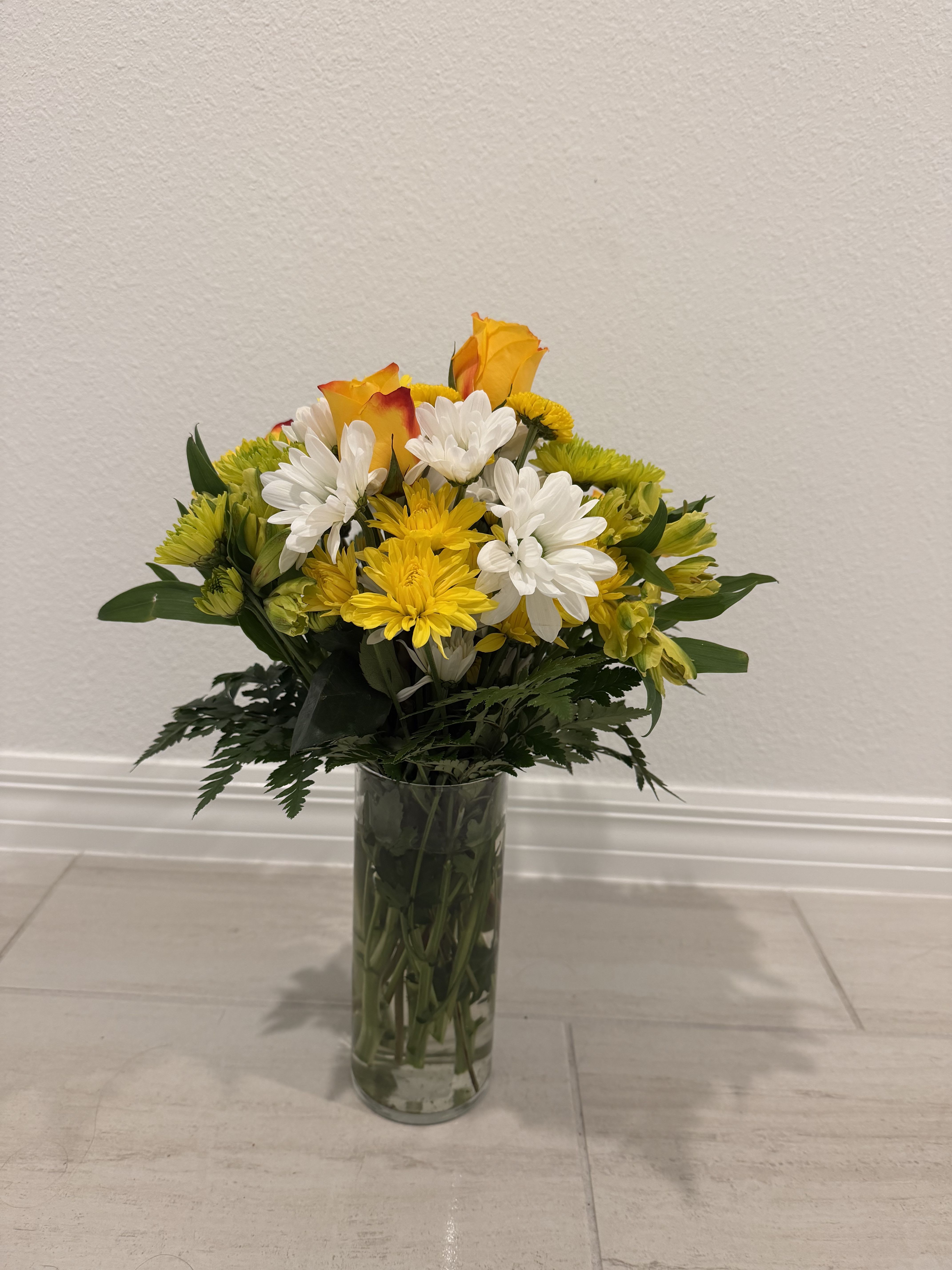 Yellow and white flower bouquet in a clear glass vase