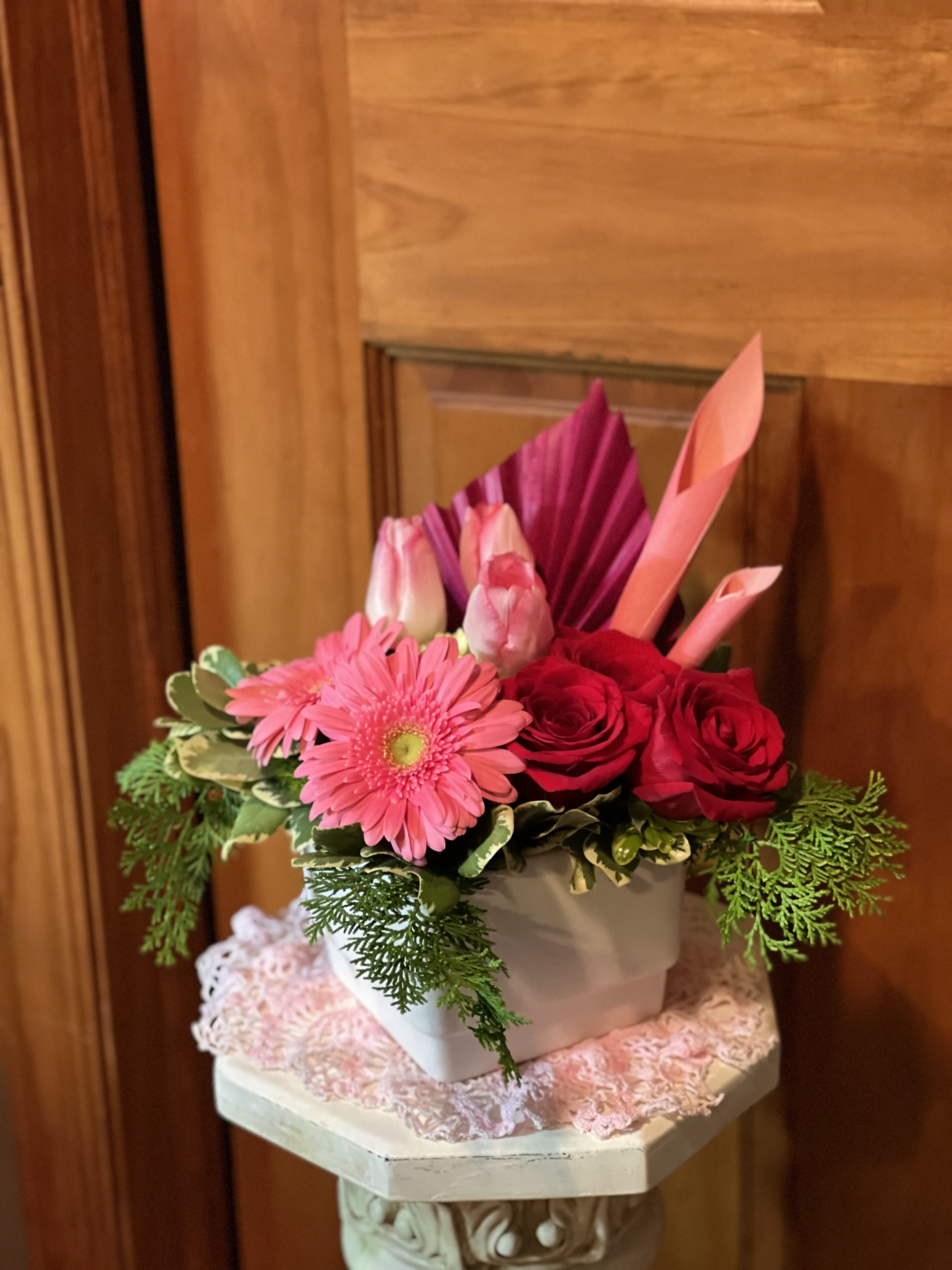 Pink gerbera daisies and red roses arranged in a white box