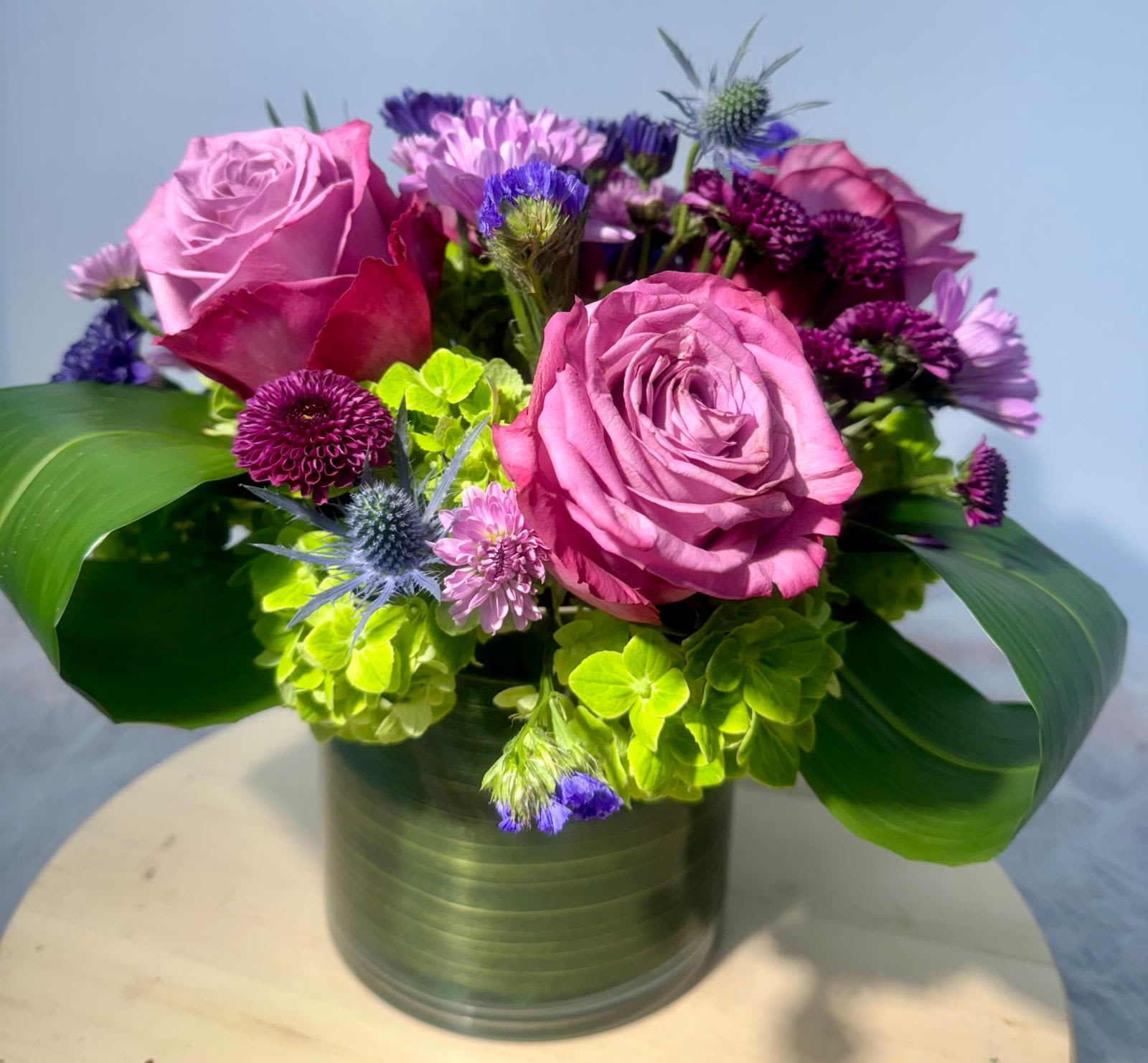 Pink roses and purple flowers arranged in a metal vase