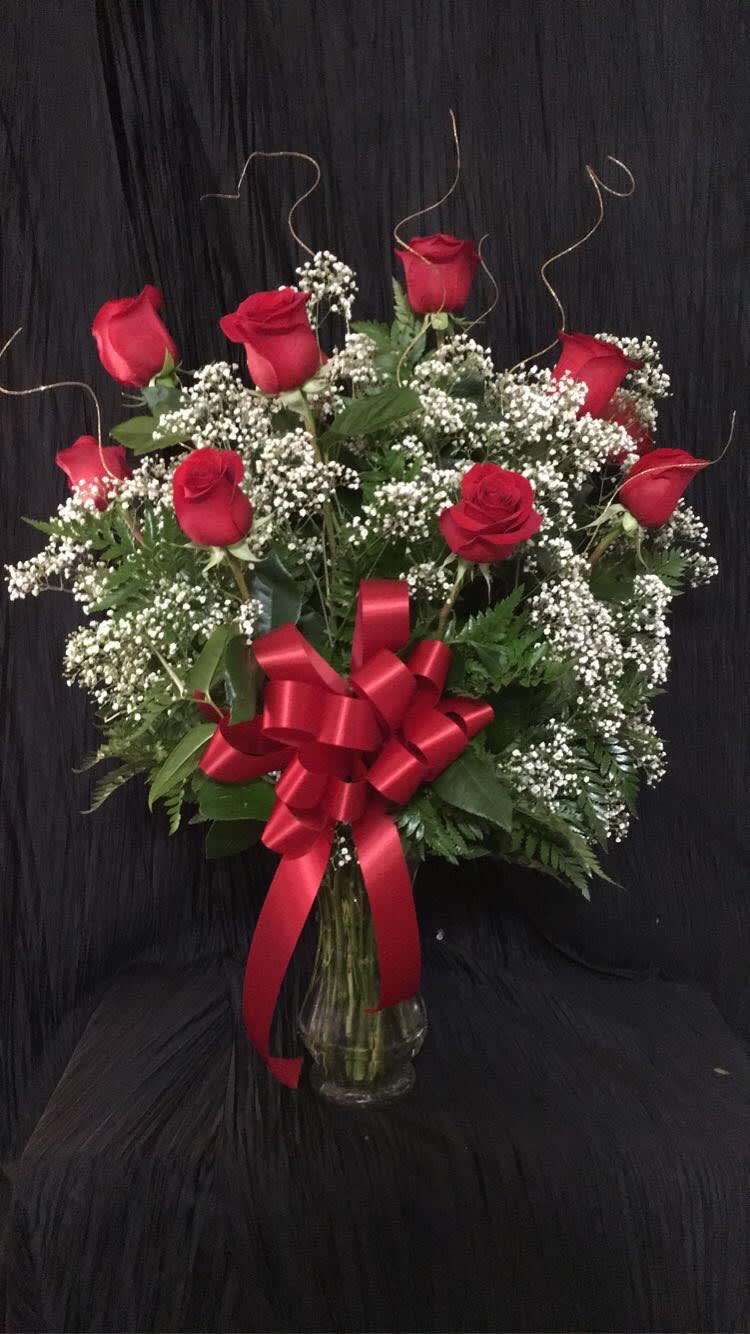 Red roses and baby's breath in a glass vase with a red bow