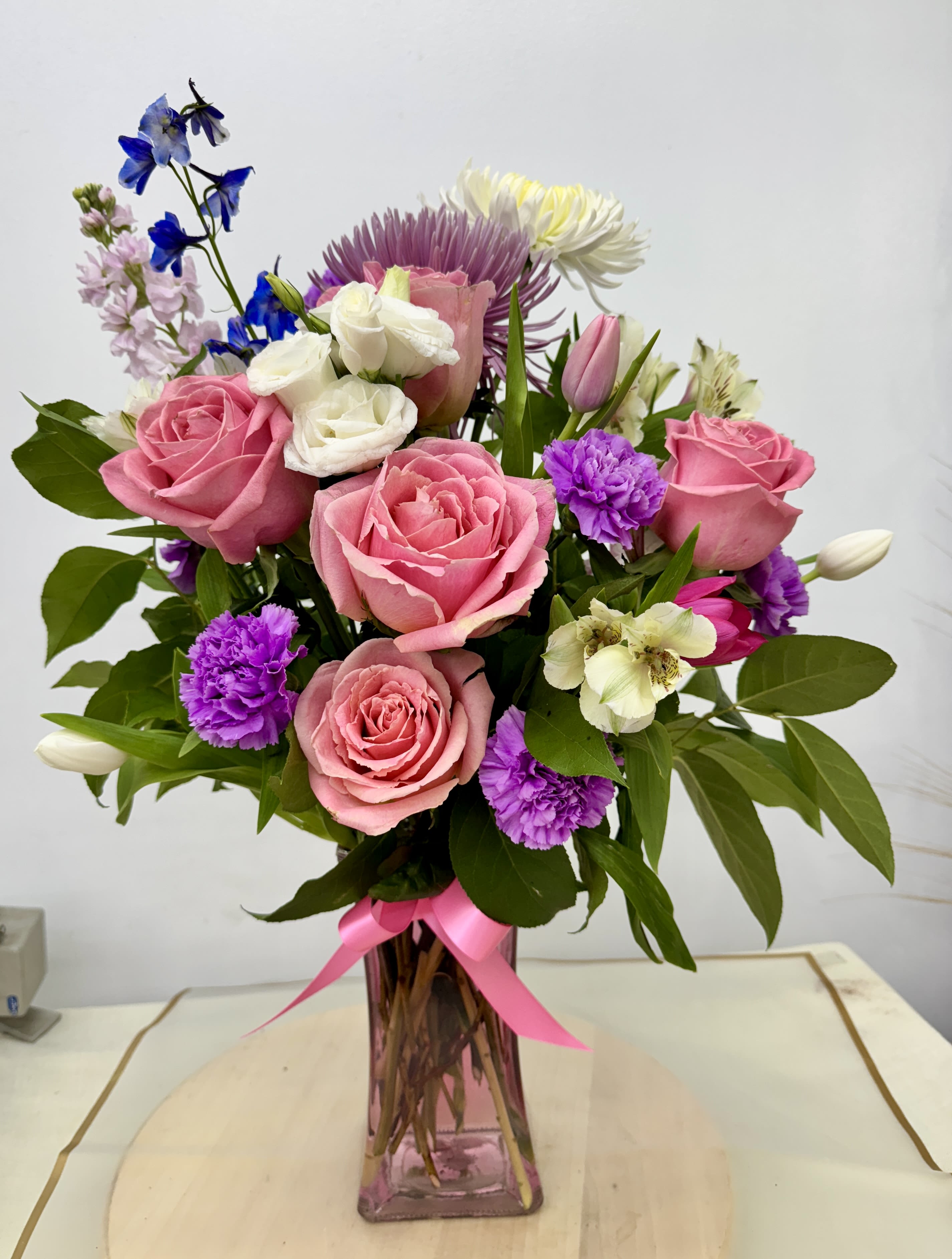Pink and white mixed bouquet in a pink glass vase with a ribbon