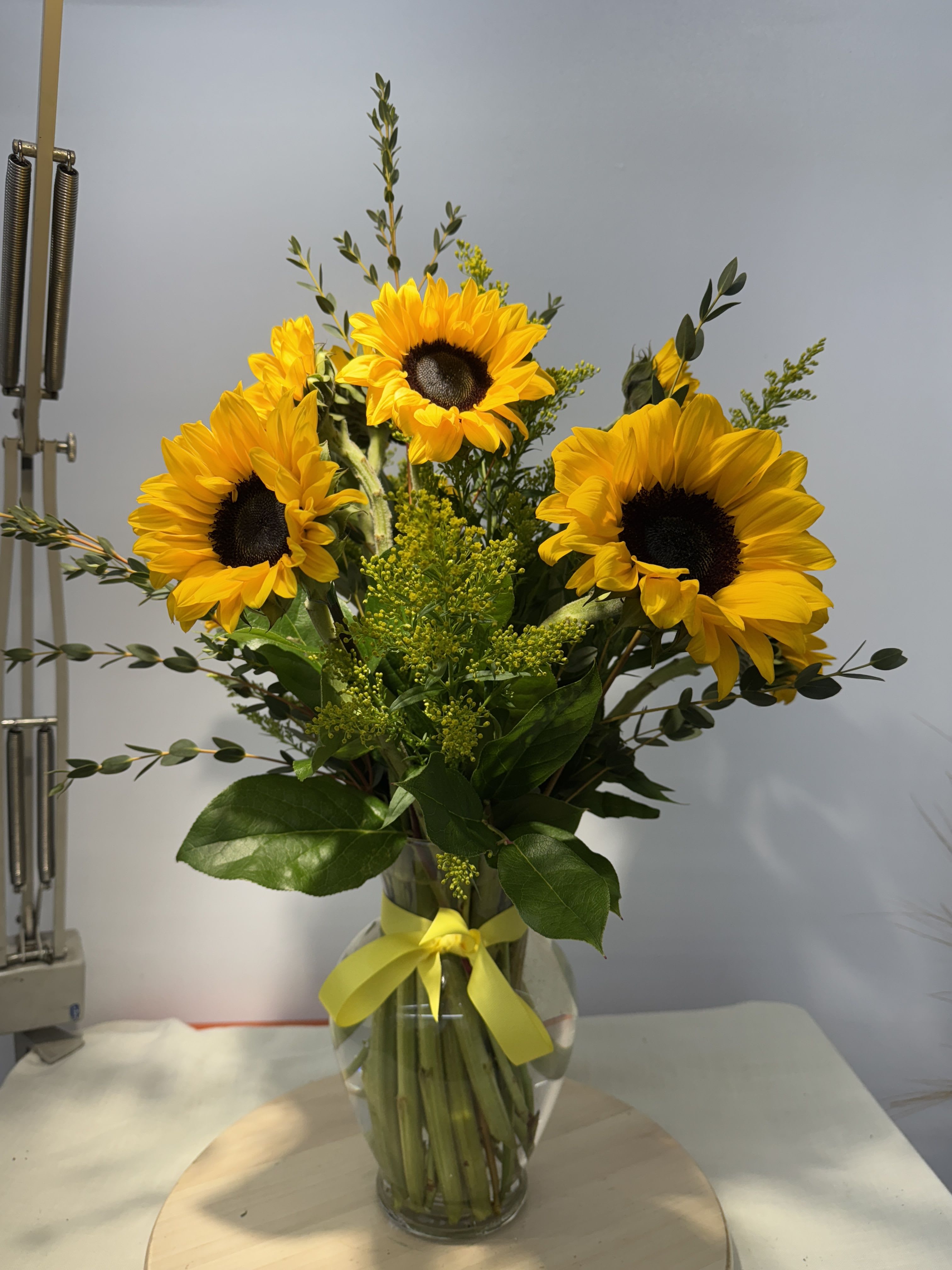 Sunflower bouquet in a glass vase with a yellow ribbon