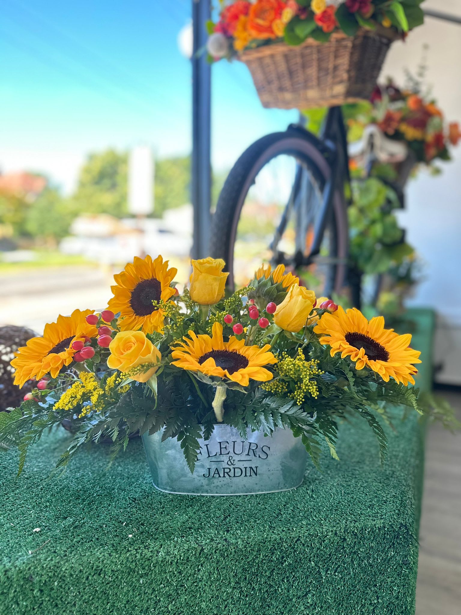 Sunflower and yellow rose arrangement in a metal container