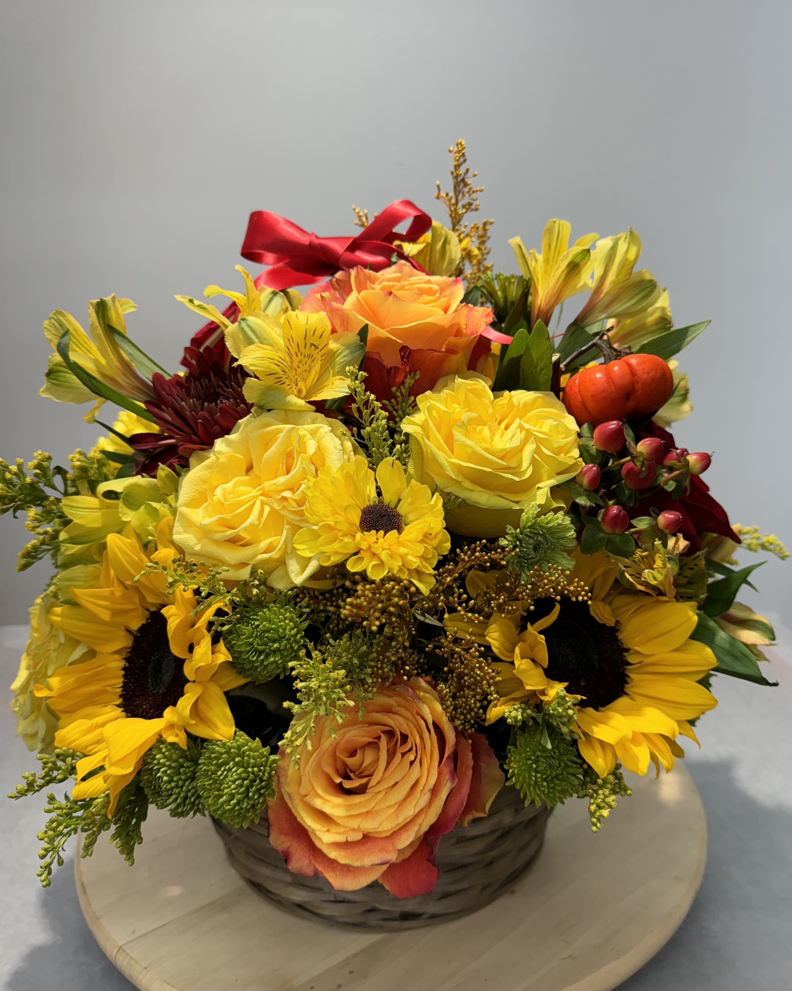 Basket arrangement with yellow roses, sunflowers, and orange blooms