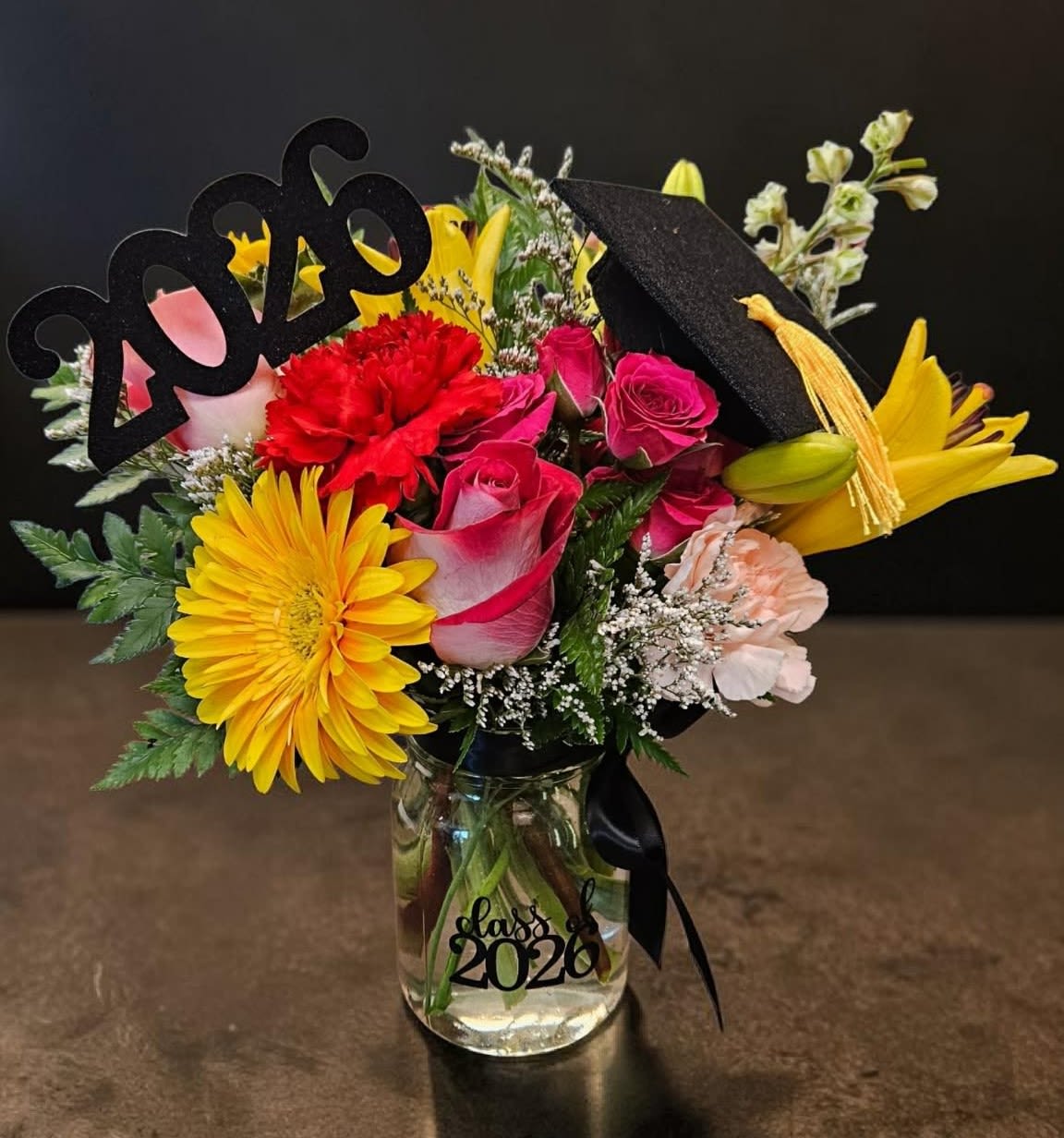 The 2026 Shining Star - This arrangement is great for the special 2026 graduate in your life, with this arrangement you can say congratulations from near or far! (Flowers are subject to change but the vase, felt grad cap, and 2026 pick will definitely be present.)