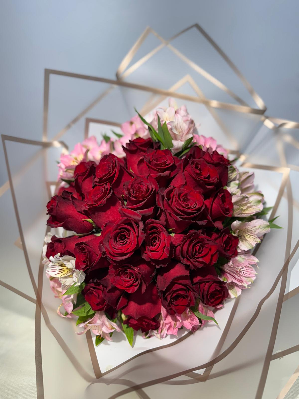 Bouquet of red roses with pink flowers wrapped in clear paper
