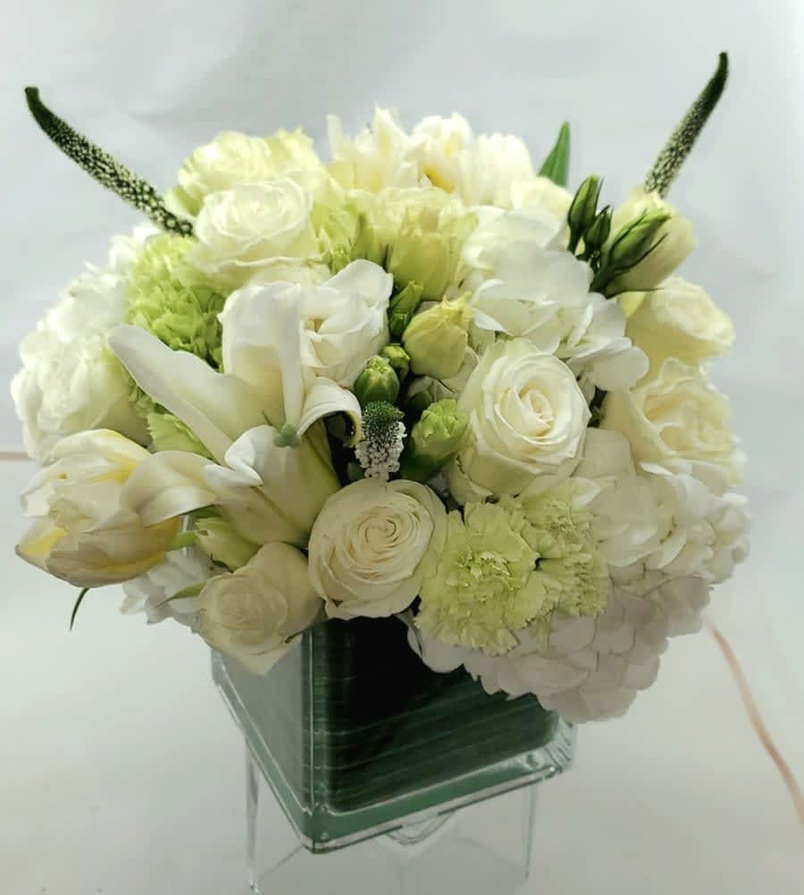 White and pale green bouquet in a clear square vase