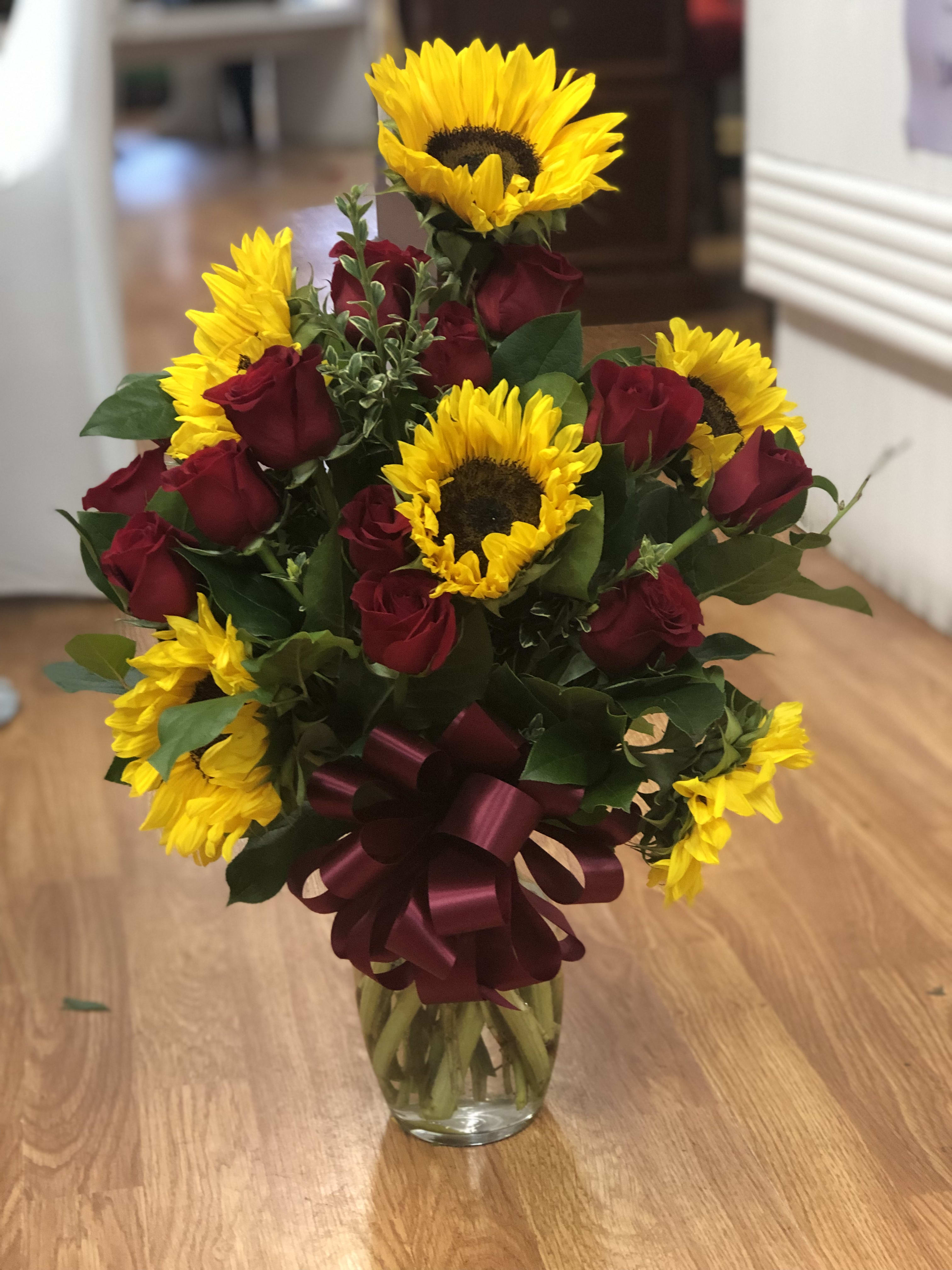 Bouquet of red roses and yellow sunflowers in a glass vase