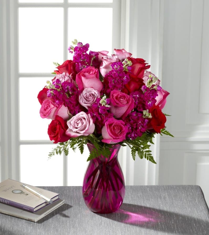 The FTD¨ Pure Romanceª Rose Bouquet - Exquisite - Utterly romantic and blossoming with your love through every blushing bloom, this gorgeous rose bouquet is out to convey your heart's every wish. Hot pink, red, and lavender roses mingle with fragrant fuchsia gilly flowers, beautifully accented with lush greens while seated in a vibrant pink glass vase. The perfect anniversary, "I love you," or Valentine's Day gift! GOOD bouquet includes 9 stems. Approx. 14"H x 11"W. BETTER bouquet includes 12 stems. Approx. 15"H x 11"W. BEST bouquet includes 17 stems. Approx. 16"H x 12"W. EXQUISITE bouquet includes 24 stems. Approx. 17"H x 14"W. 