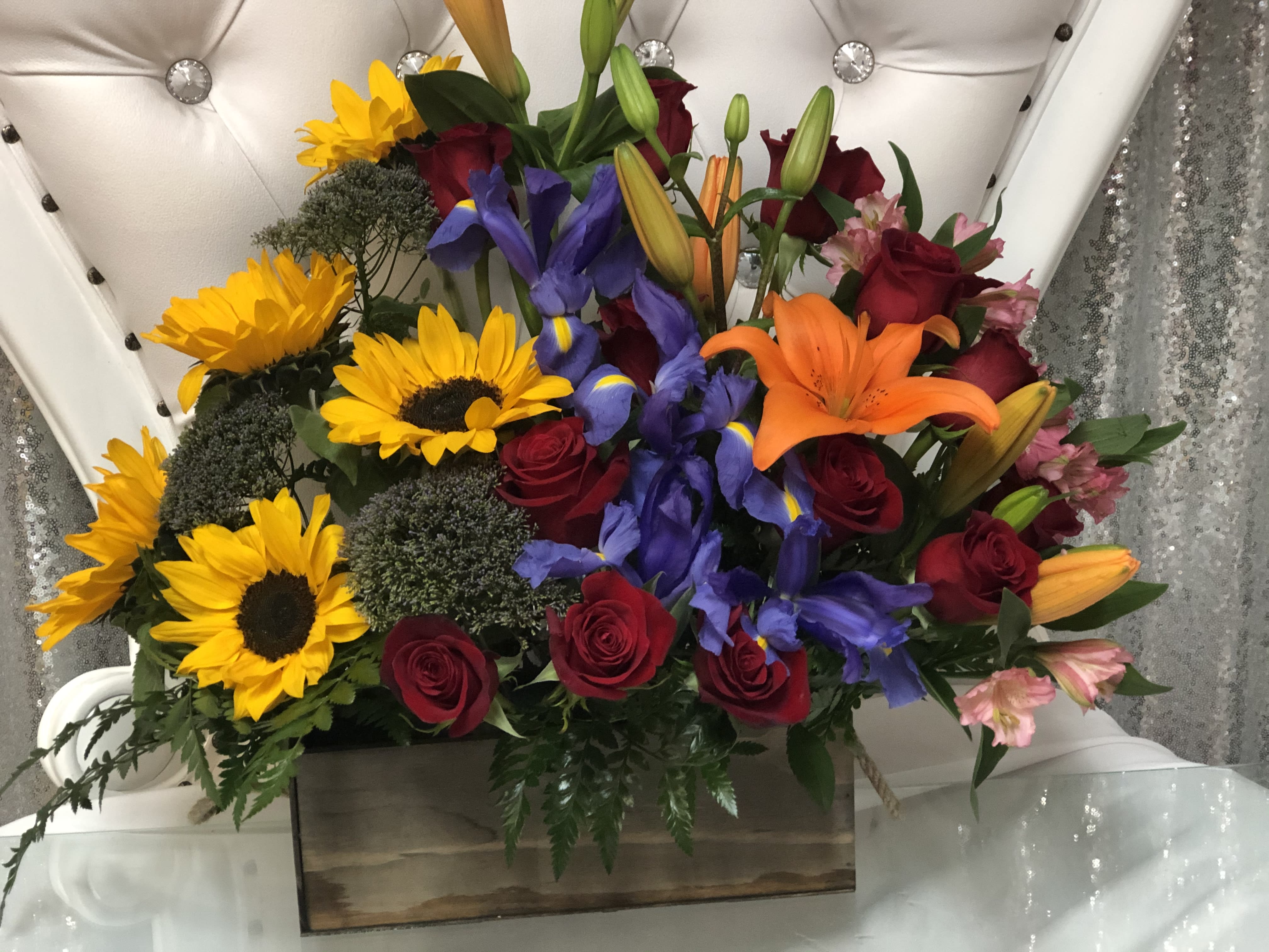 Mixed bouquet with sunflowers, roses, lilies, and irises in a wooden box
