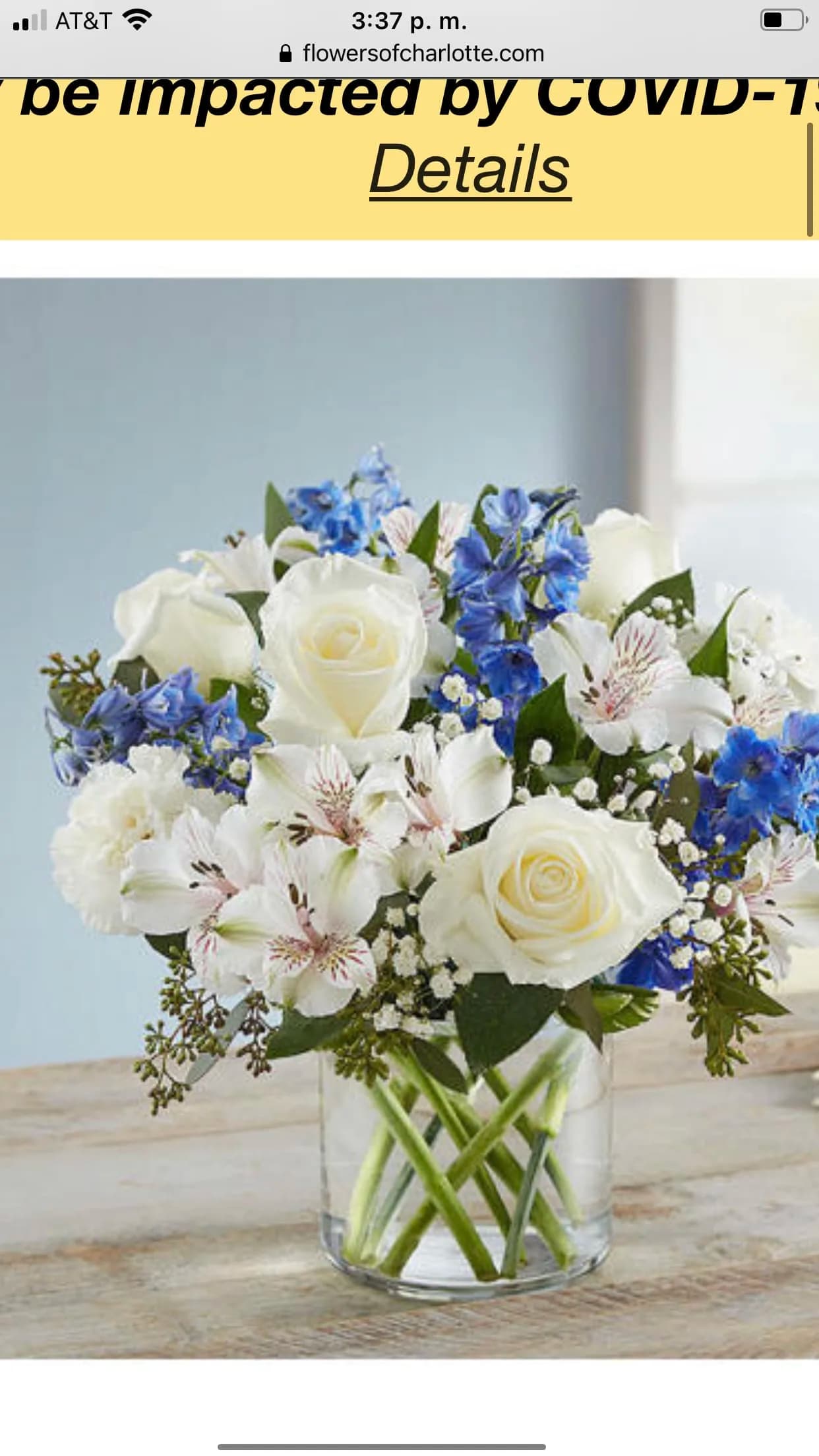 White roses and blue flowers arranged in a clear glass vase