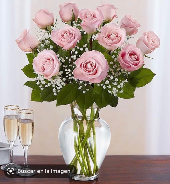 Pink roses arranged in a clear glass vase with baby's breath