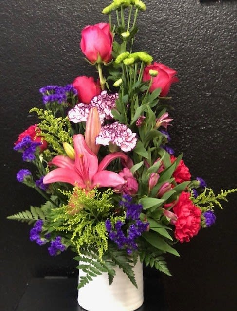 Tall mixed bouquet in a white vase with pink roses, lilies, and purple accents