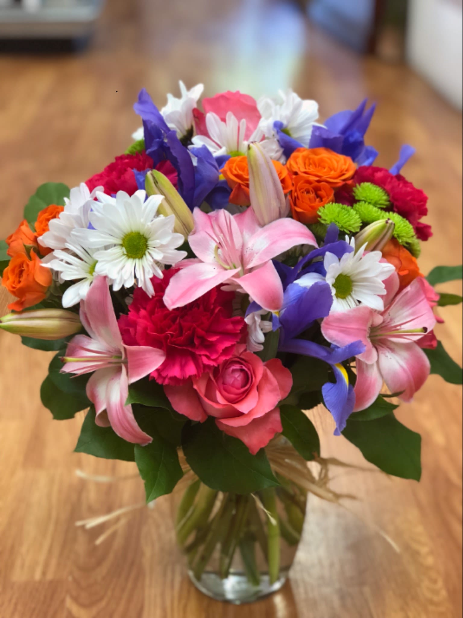 Mixed bouquet of pink, purple, orange, and white flowers in a glass vase