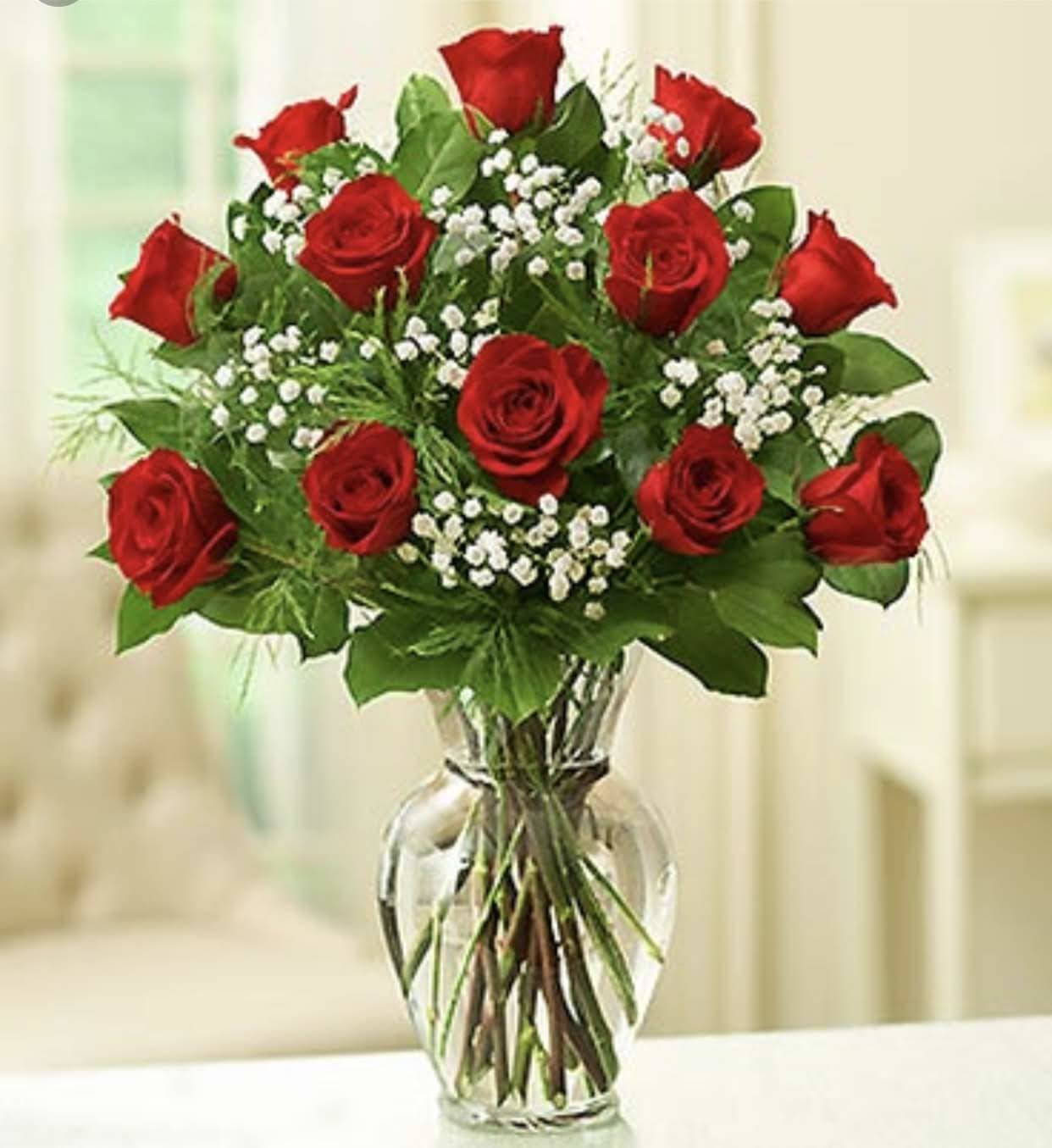 Red roses arranged in a clear glass vase with white filler flowers