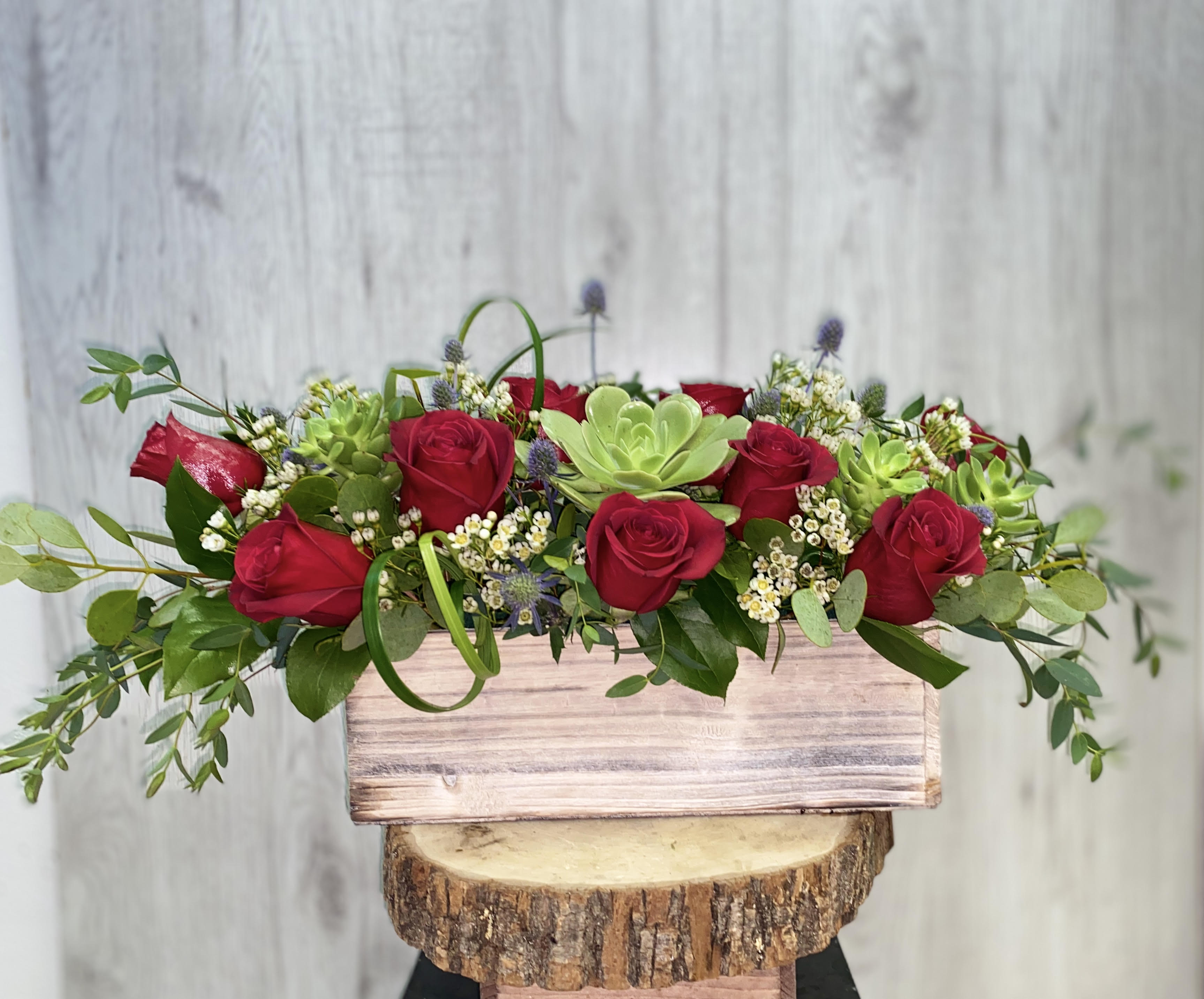 Red roses and succulents in a rustic wooden box
