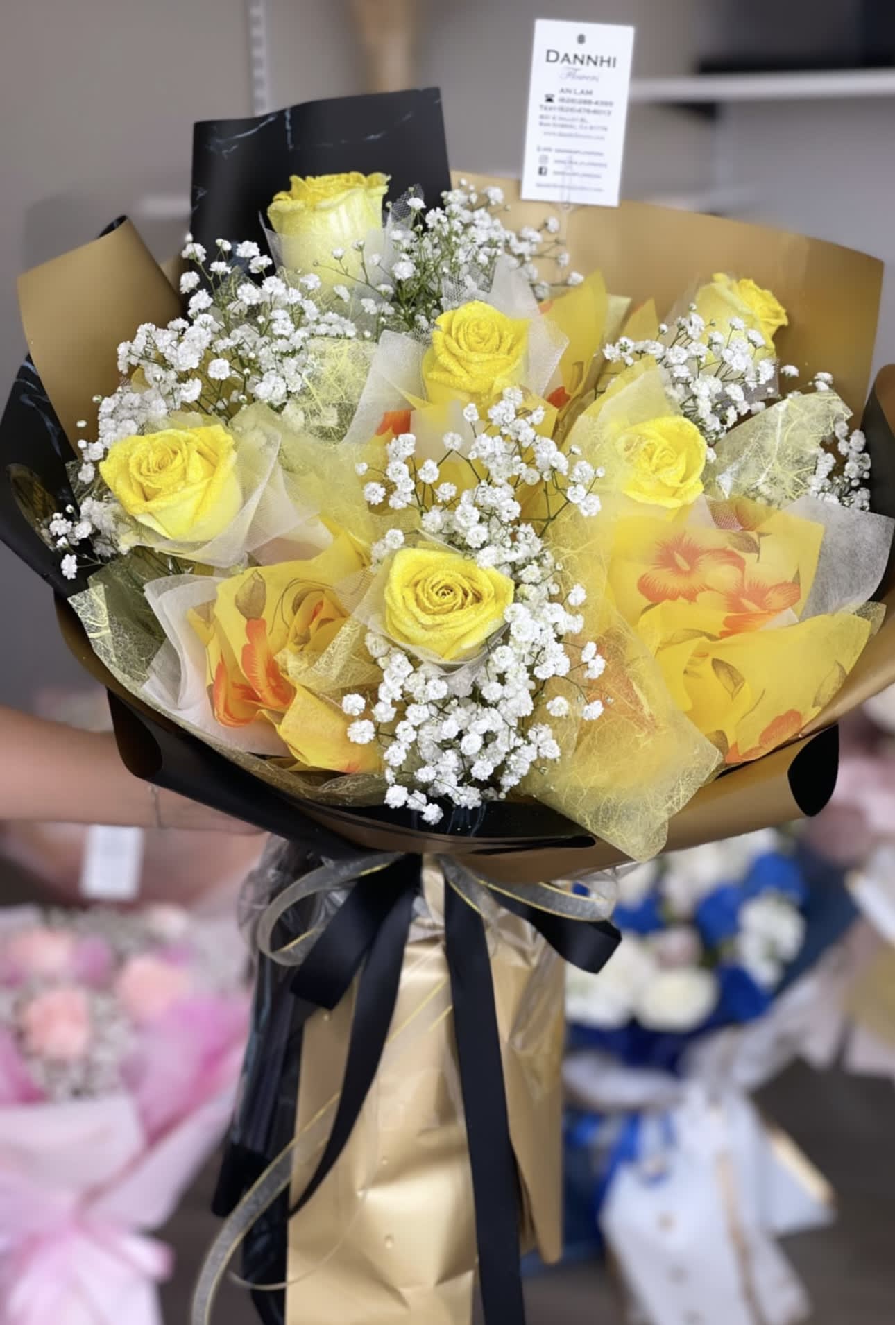 Bouquet of yellow roses with white baby's breath in gold and black wrap