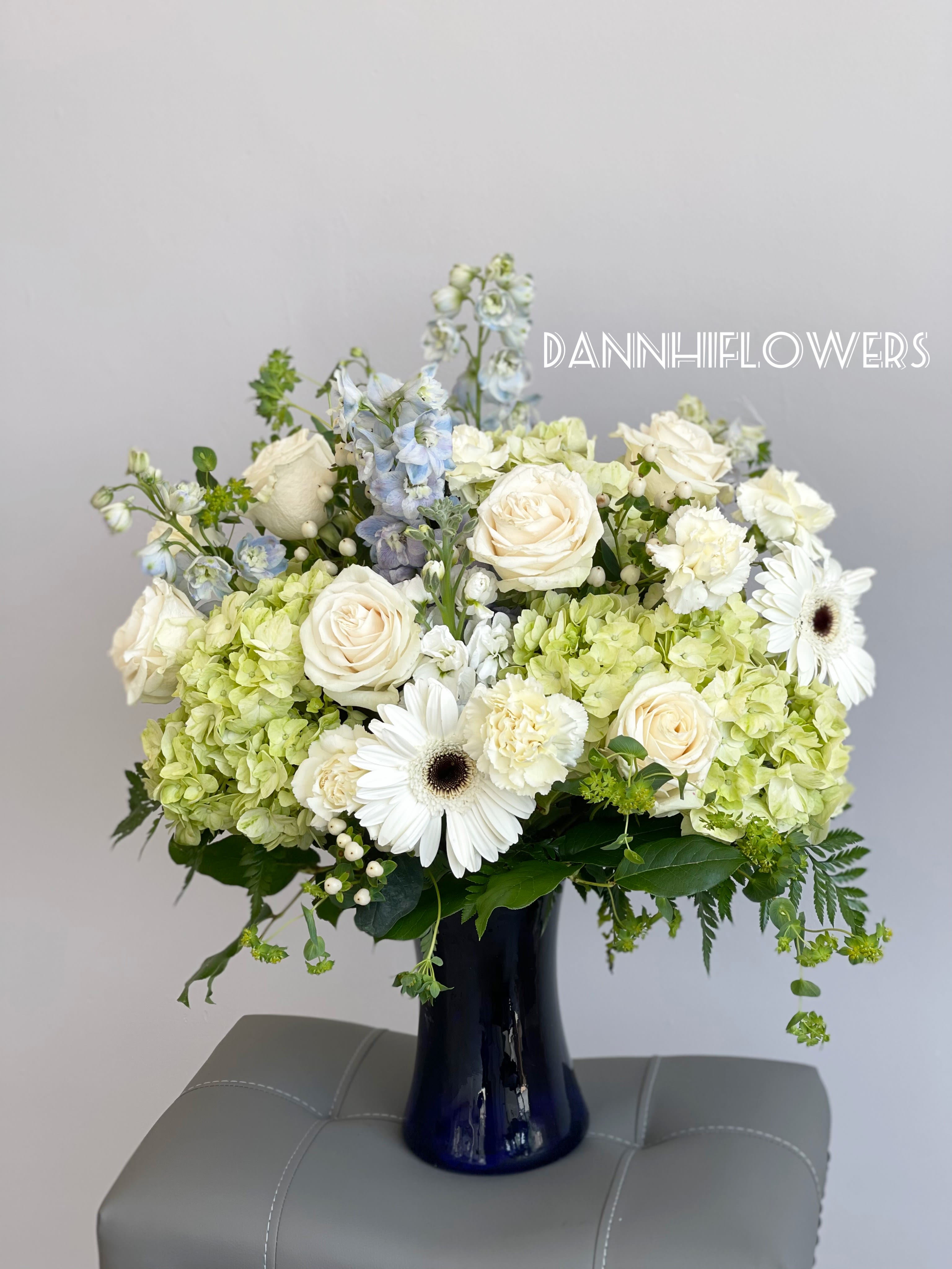 White roses and green hydrangeas in a dark blue vase