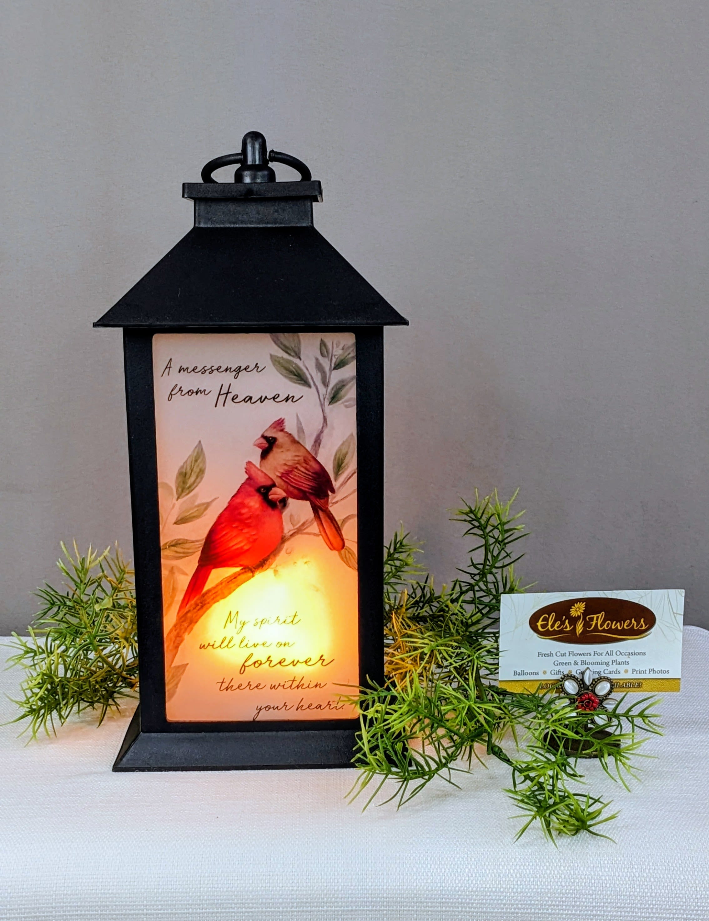 Black lantern with a memorial card and faux greenery sprigs