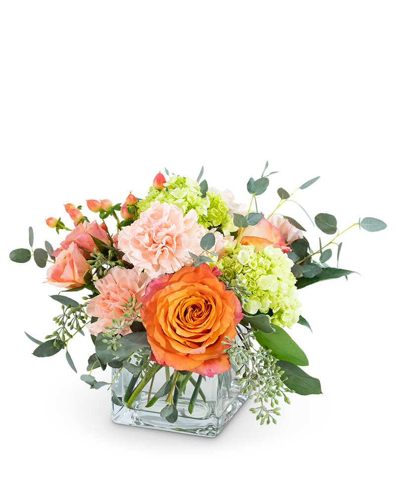 Bouquet of orange and peach roses with pink carnations in a glass vase