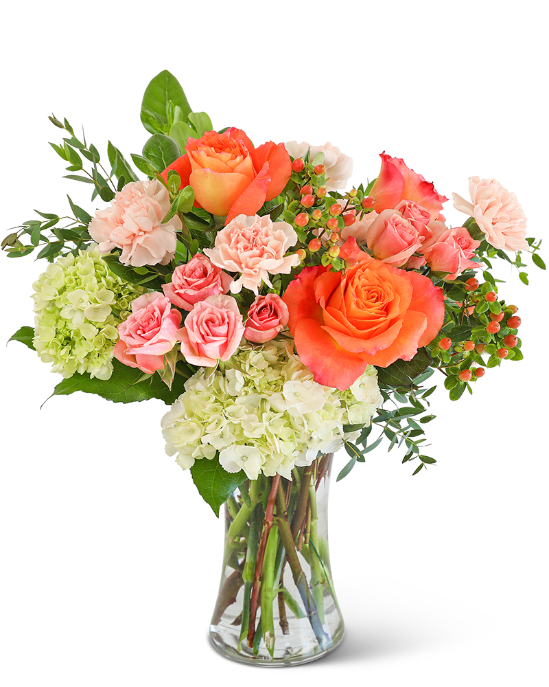 Bouquet of orange and pink roses with pale hydrangeas in a clear glass vase