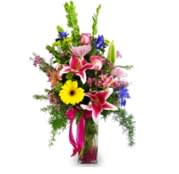 Tall mixed flower arrangement in a glass vase with bright pink and yellow blooms