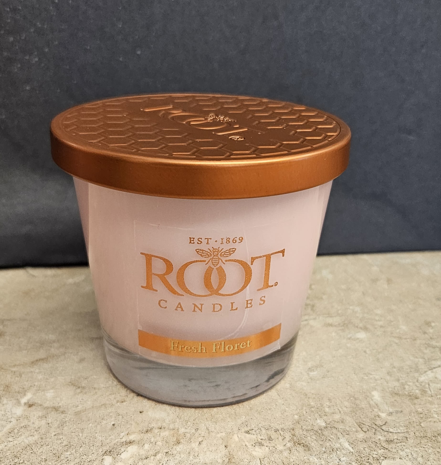 Root Candle Fresh Floret S - A floral-scented glass jar candle that feels like a mini bouquet for the senses - the Root Candle Fresh Floret S is a floral home fragrance perfect as a hostess gift, a thoughtful birthday add-on, or a "just because" surprise for someone who loves cozy, scented spaces. This candle's fresh floral aroma evokes the warmth and calm of a small arrangement without actual flowers, making it a great choice when you want to give the impression of blossoms for anniversaries, thank-yous, or housewarming moments.  The candle sits in a clear glass jar topped with a warm copper-colored metal lid and features soft white wax that complements orange, white, and black-accented packaging or gift wrapping. Its understated, clean presentation works well in gift sets, on bedside tables, or in living rooms where a gentle floral scent enhances the atmosphere. Simple care: keep wick trimmed to 1/4", burn on a stable, heat-resistant surface, and follow basic candle-safety guidelines to ensure even melting and long-lasting fragrance.
