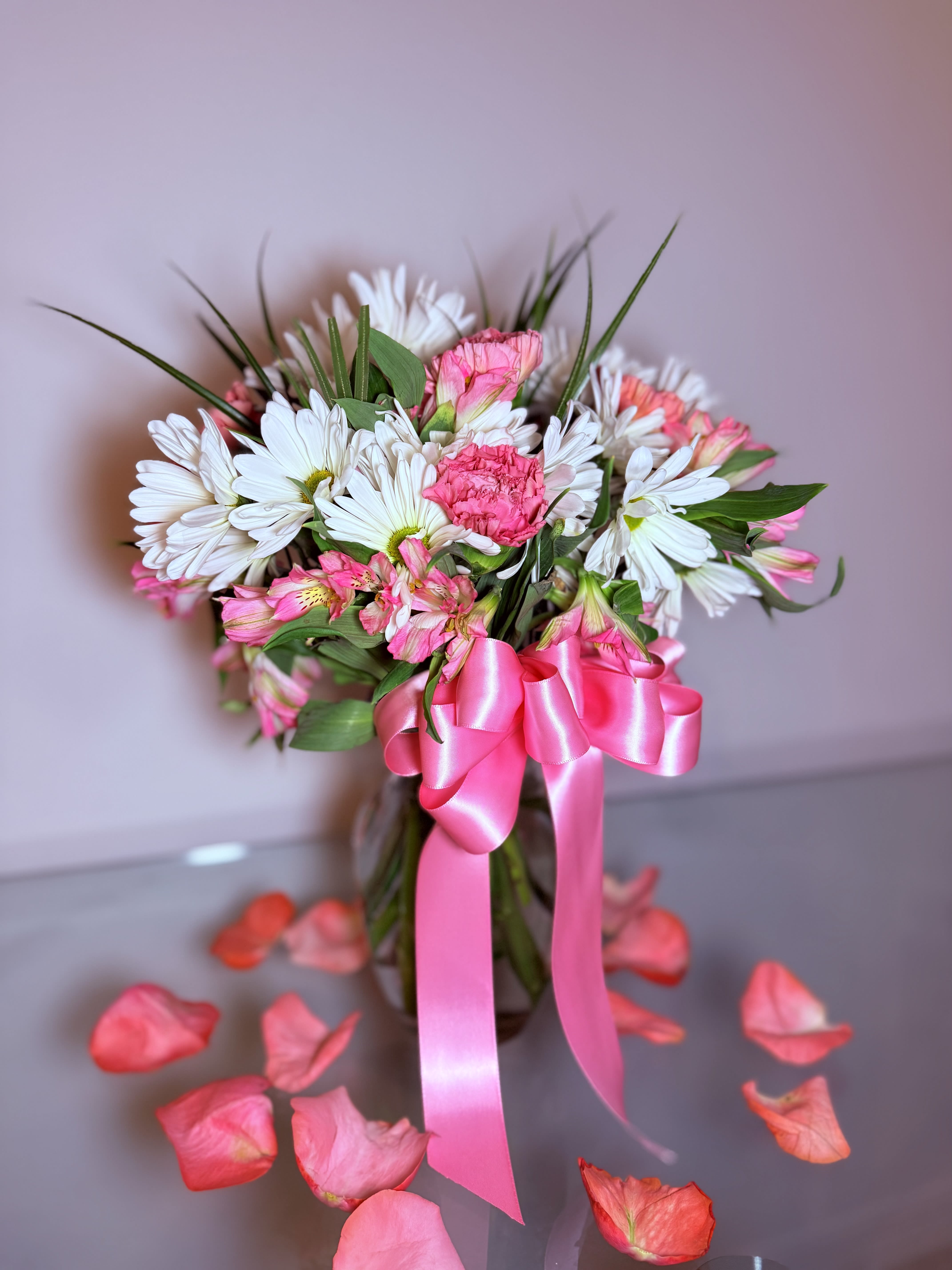 Pink and white bouquet in a glass vase with a satin ribbon
