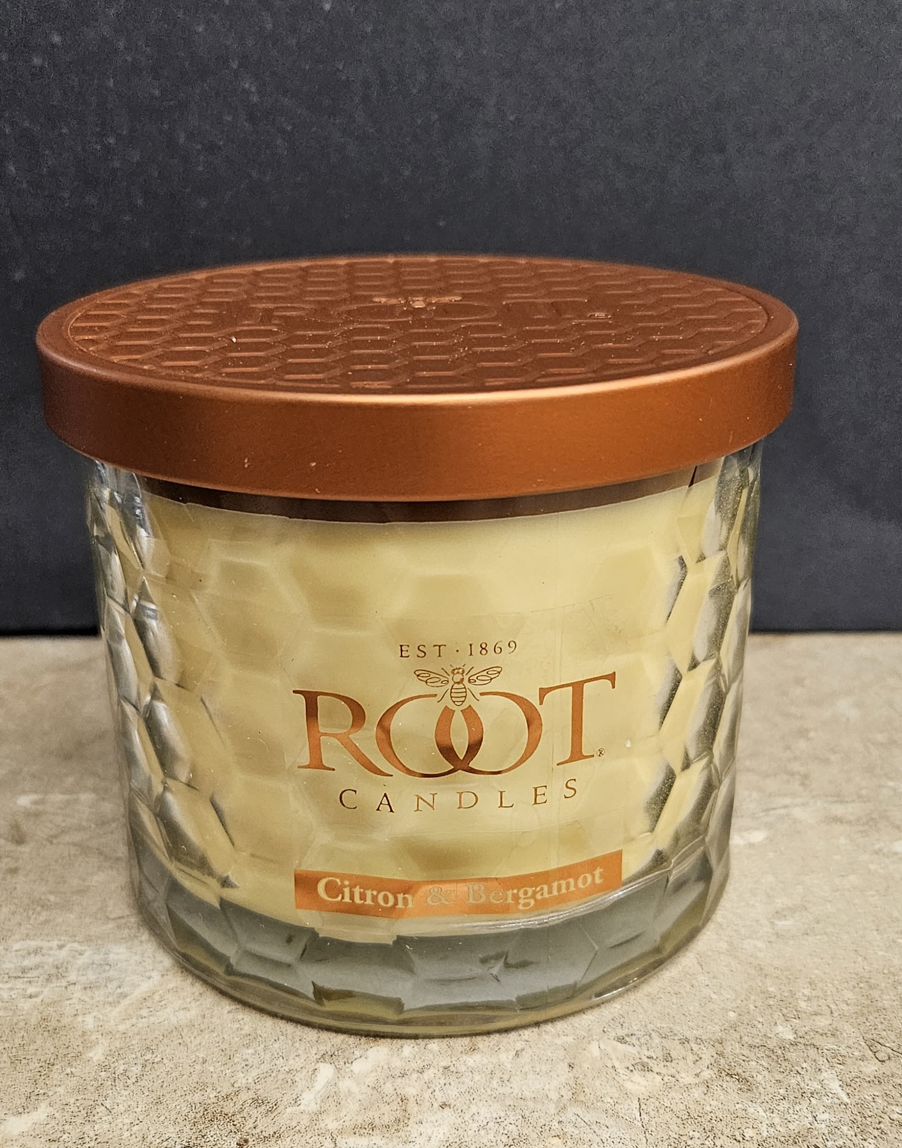 Root Candle Tea Leaf &amp; Honey 3 wick - Warm amber and creamy tones set a cozy mood with this Root Candle Tea Leaf &amp; Honey three-wick candle - a perfect housewarming or thank-you gift for someone who loves a gentle, inviting scent. As a home fragrance item for everyday use, it gives the person you're thinking of an immediate feeling of warmth and calm, ideal for settling into an evening at home or accenting a relaxing bath.  Presented in a clear, faceted glass jar with a brown metal lid, the single-scent candle carries a clean label reading Root Candles and Citron &amp; Bergamot. The three-wick format fills rooms more quickly and evenly than a single-wick candle, and the compact glass adds decorative warmth on a mantel, bedside table, or entry console. Recommended for gifting and easy ordering, it arrives ready to nestle into a new home or to say "thinking of you" with enduring, subtle fragrance.
