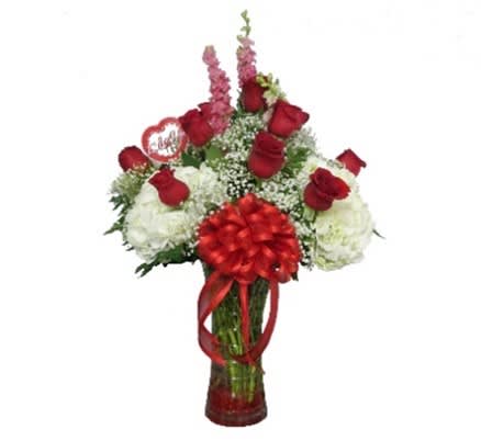 Red roses and white flowers in a glass vase with a red bow