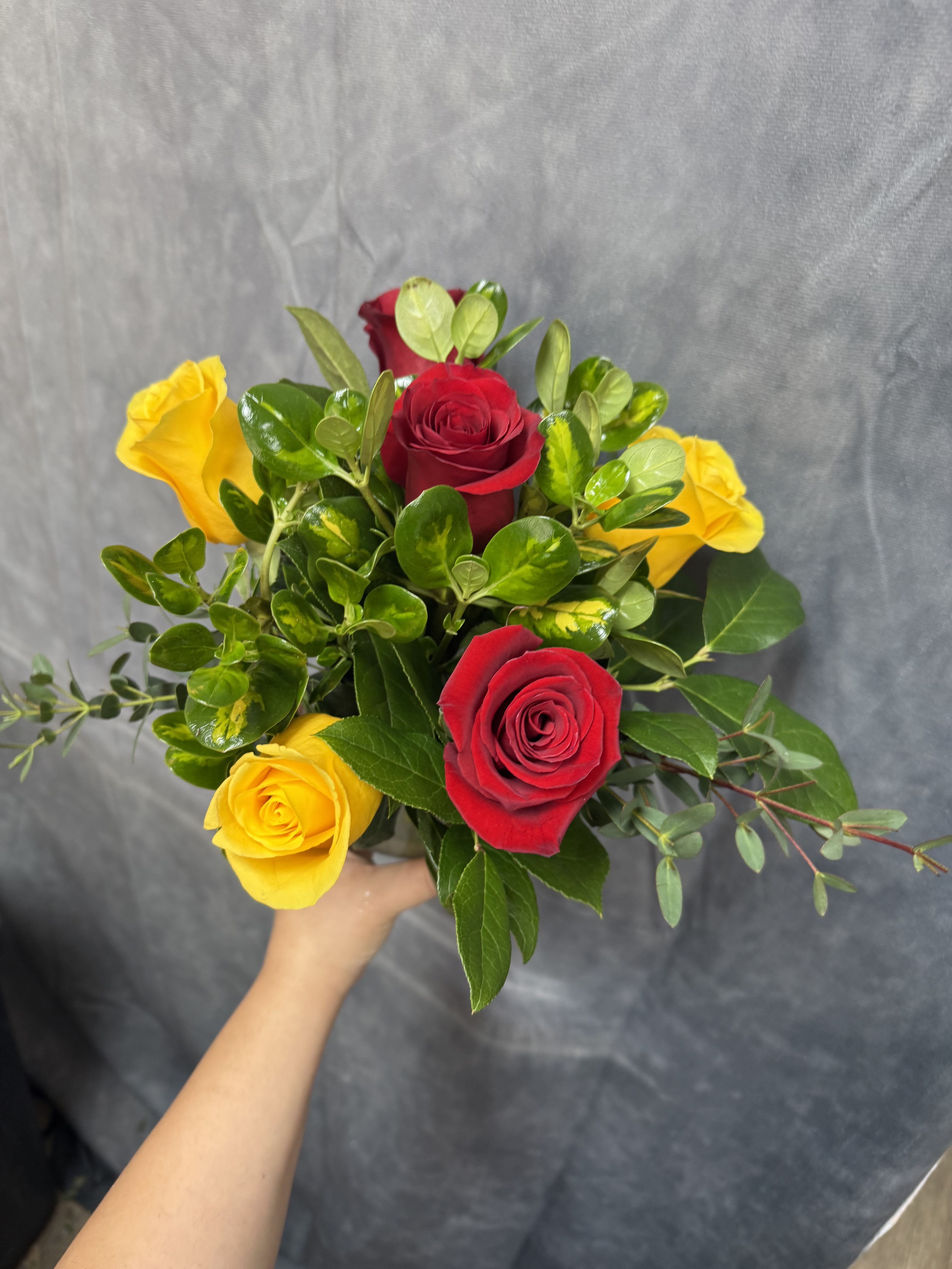 Mix roses posy vase - Red and yellow roses with glossy green foliage in a clear glass vase-cheerful, compact posy perfect for birthdays, anniversaries, or just because.