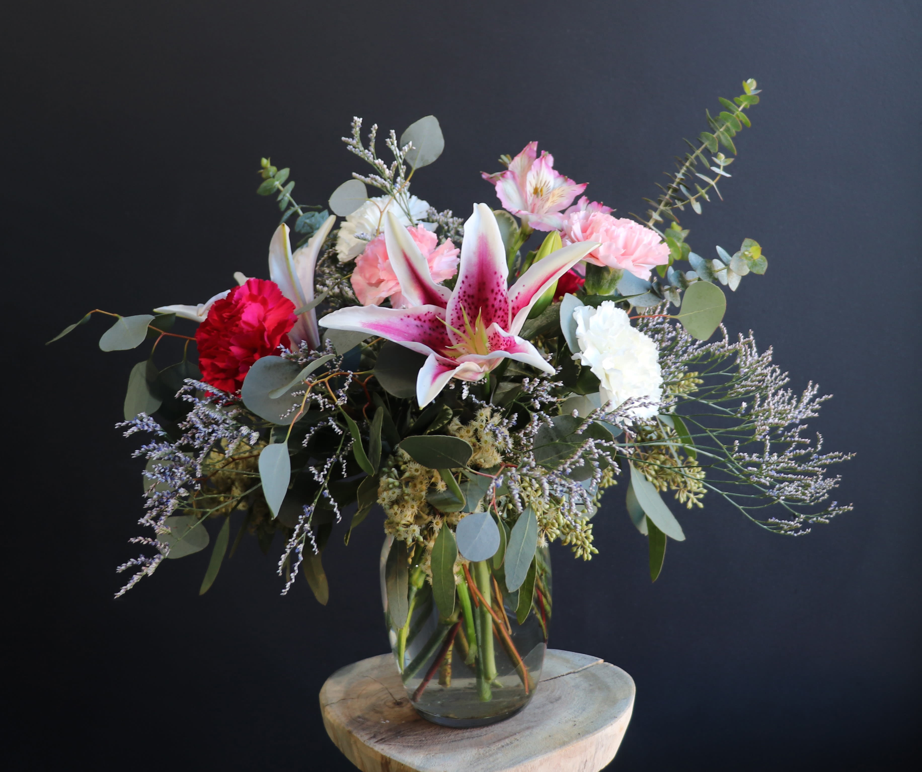 Mixed bouquet with pink lilies, carnations, and eucalyptus in a glass vase