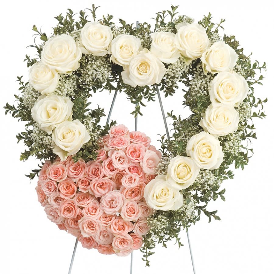 Heart-shaped floral wreath with white and pink roses on a stand