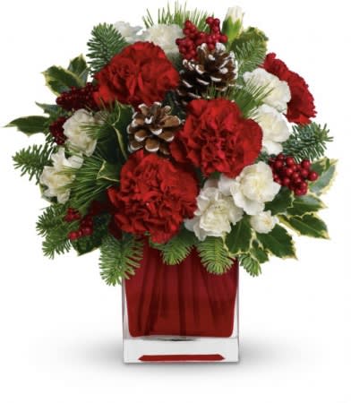 Red and white floral arrangement in a clear vase with pinecones and berries