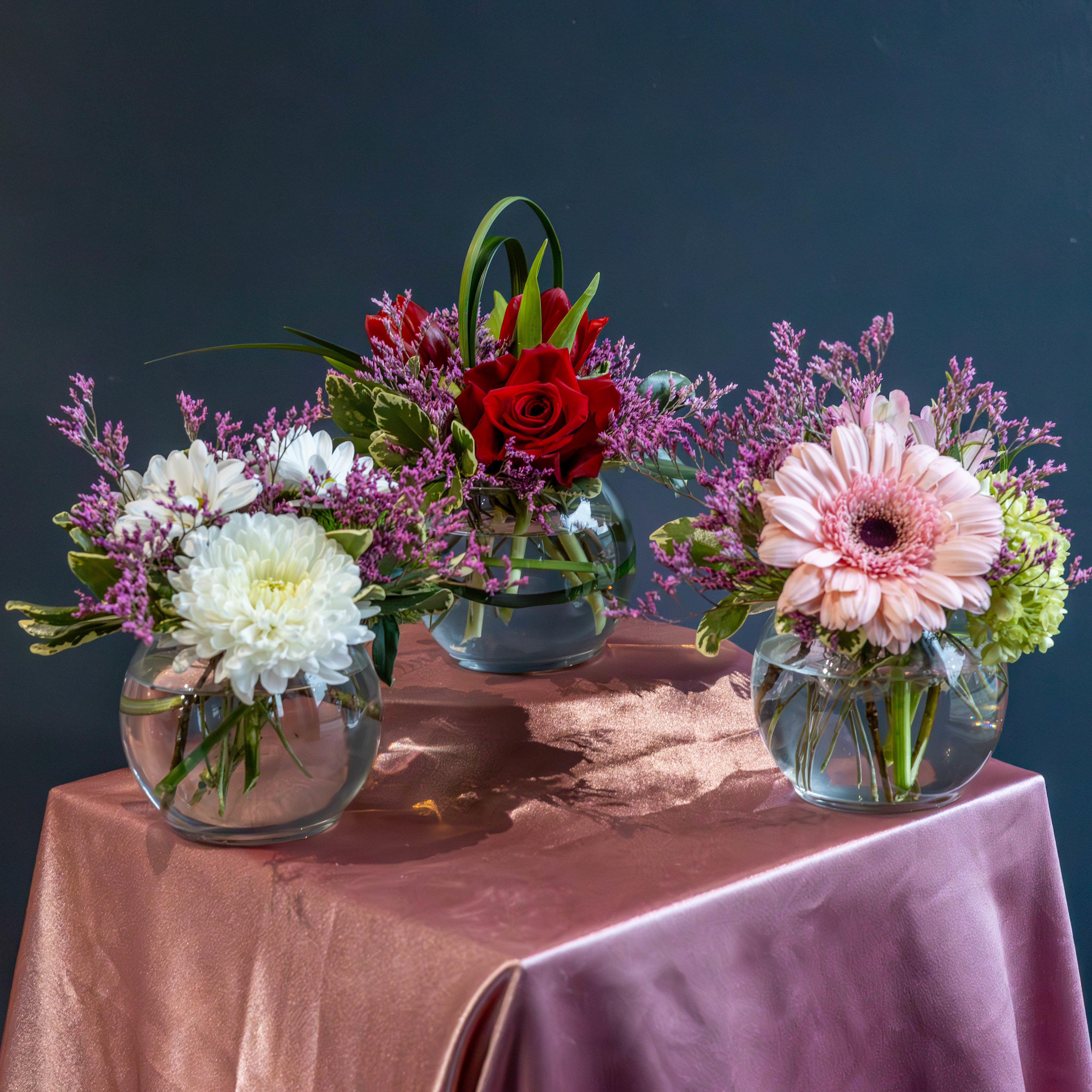 Three's Company - Celebrate love in all its beautiful forms with our Triple the Love Bubble Bowl Collection, a Valentine’s arrangement designed for sharing. This set includes three charming bubble bowl arrangements, each thoughtfully styled with fresh, vibrant blooms and lush accents that feel modern, elegant, and heartfelt.  Perfect for spreading love far and wide, this collection allows you to gift one arrangement to Mom, Grandma, an in-law, and someone else special in your life—because Valentine’s Day isn’t just for one person. These sweet arrangements are also wonderful for a sister, aunt, best friend, daughter, teacher, coworker, or anyone who deserves a little extra love and appreciation.  Whether displayed together or shared individually, each bubble bowl makes a meaningful statement: you’re loved, remembered, and celebrated. It’s the perfect way to turn one Valentine’s gift into three unforgettable moments.