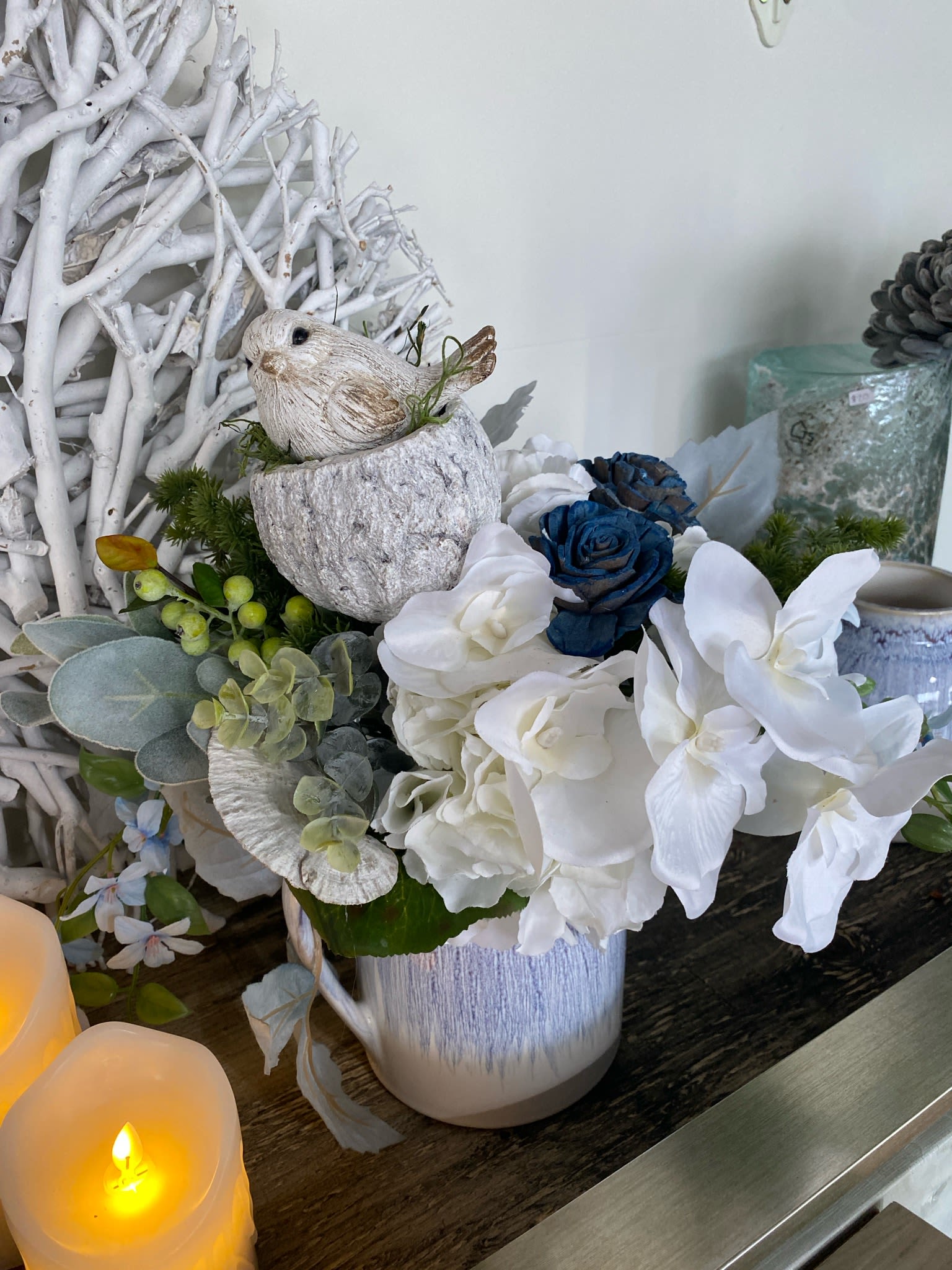 White and blue floral arrangement in a ceramic pot with a bird figurine