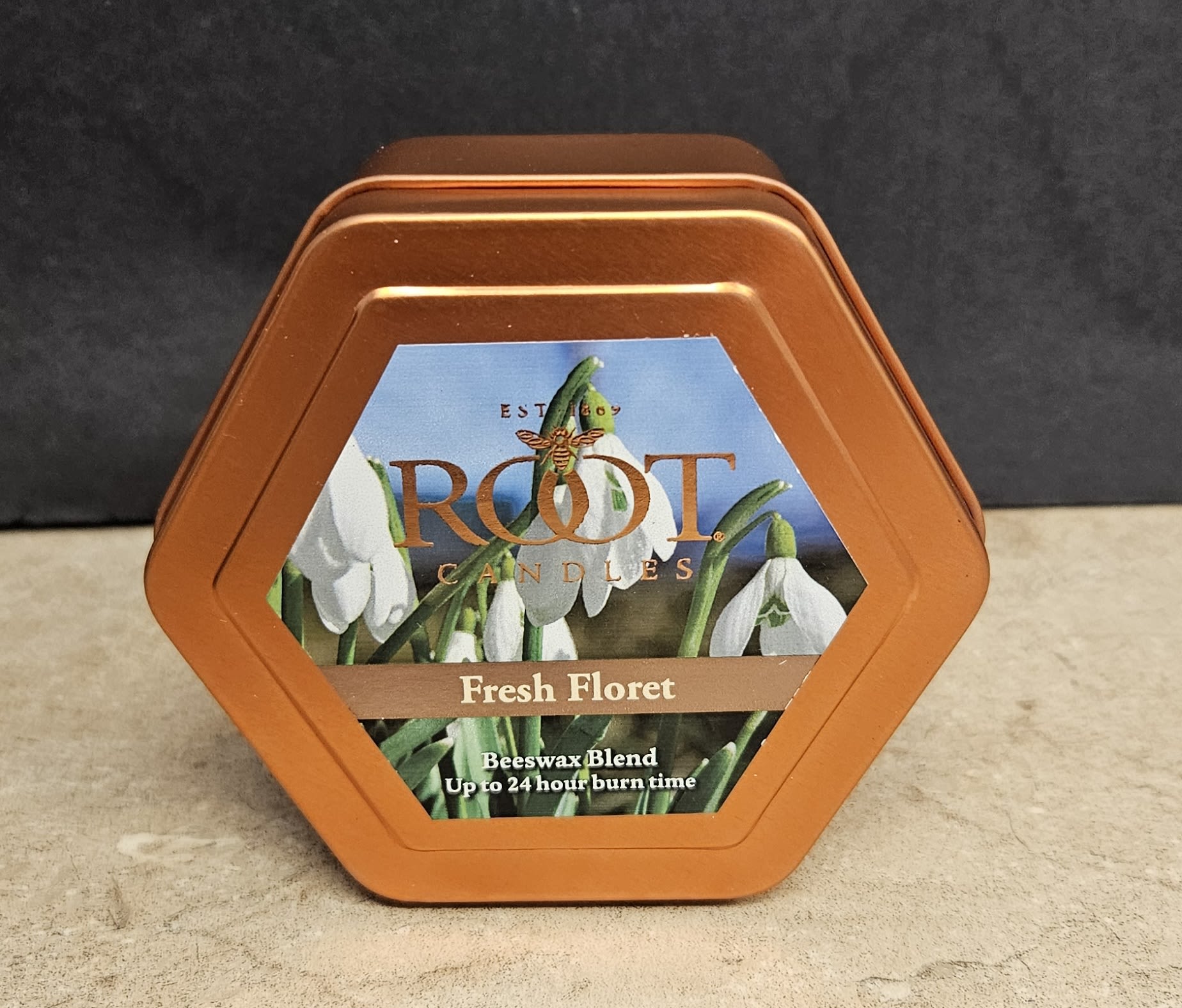 Root Candle Fresh Floret Tin S - A compact, botanical-scented gift that brightens a room: this flower arrangement-style gift pairs a copper-orange hexagonal metal candle tin with a soft floral label to create the feel of a seasonal gift for a home or hostess. As a home fragrance gift for occasions like a housewarming or a thoughtful "thinking of you" present, the Fresh Floret tin reads like a tiny bouquet in metal-fresh, clean, and quietly decorative-so the person you're giving it to will feel cared for and cozy.  The tin features a printed label depicting white, snowdrop-like blossoms against a calming blue field, accented by green foliage tones that play nicely with the warm orange metal finish. Inside is a beeswax-blend candle (label reads "Fresh Floret" and "Beeswax Blend"), presented in a hexagonal copper-orange container that makes a neat tabletop accent. Small and seasonally styled, it's perfect to tuck into a gift basket, place on a bedside table, or send as a simple yet elegant token that refreshes a space with light and scent.