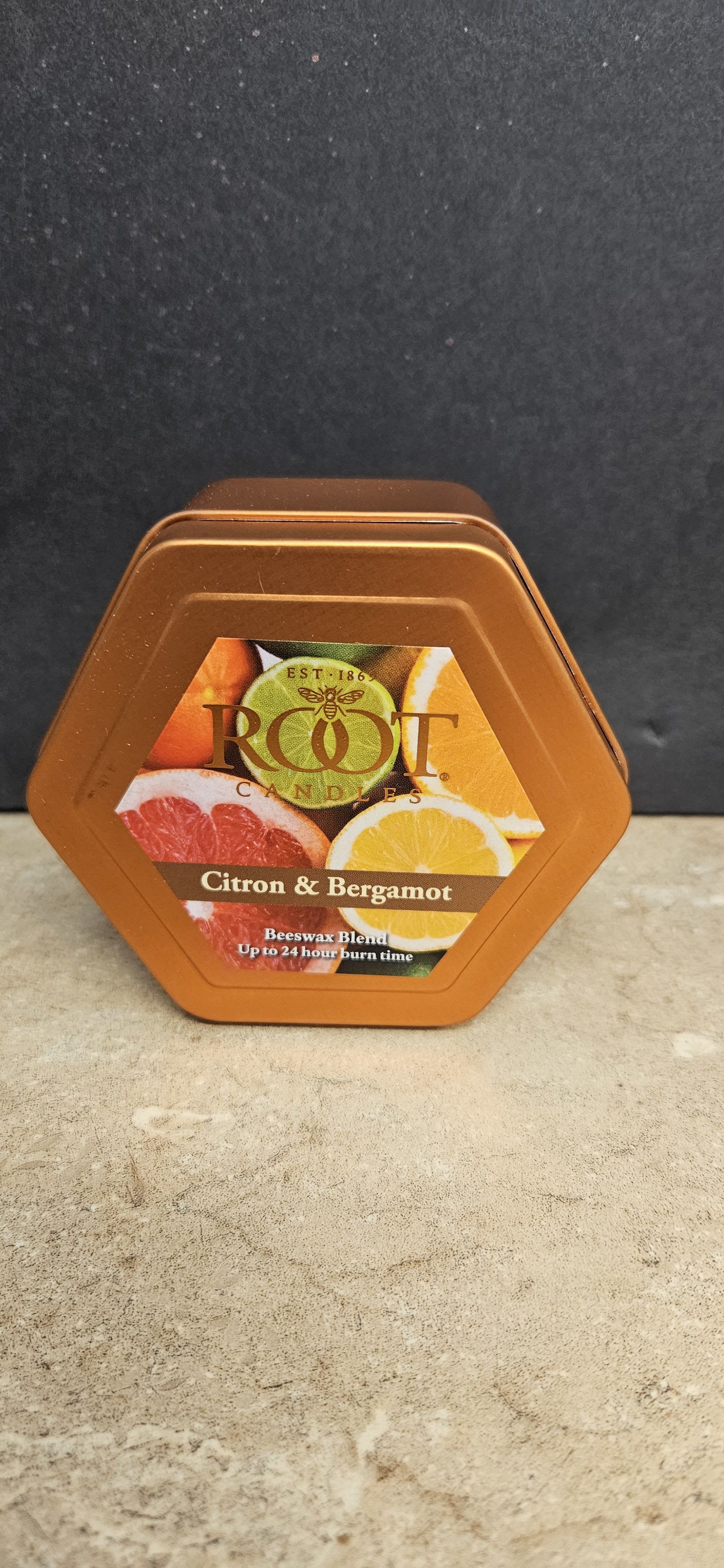 Root Candle Citron &amp; Bergamot Tin S  - Sun-kissed citrus fragrance in a compact metal tin-this Citron &amp; Bergamot candle tin is a cheerful gift for a birthday, housewarming, or to brighten someone's day. The hexagonal orange metal candle tin with a bright label of citrus slices reads fresh and clean, the perfect complement to a cheerful flower arrangement or a thoughtful stand-alone present for the person you're thinking of.  Made with a beeswax blend and presented in a durable metal candle tin, the scent combines lively citron and bergamot for a bright, uplifting aroma. The label and tin use warm orange, yellow, and brown tones that pair beautifully with autumnal bouquets or sunny yellow and orange blooms. Up to 24 hour burn time gives the recipient plenty of enjoyment; the tin's small, gift-ready size makes it easy to add to same-day floral orders or send as a cozy accent for any occasion.
