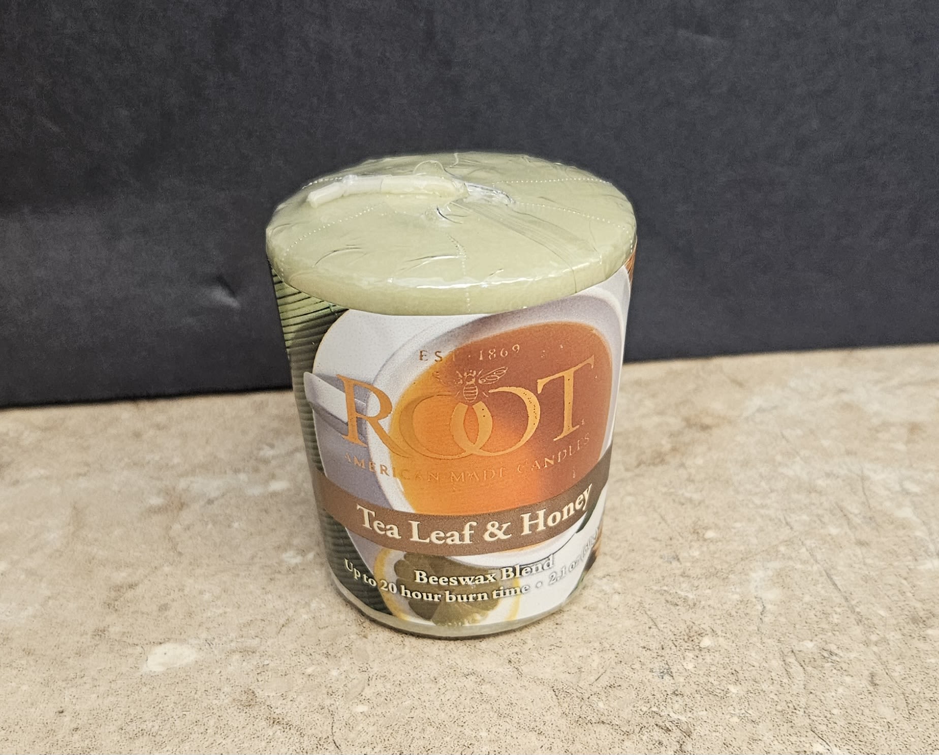 Root Candle Tea leaf &amp; Honey Votive - A cozy, gift-ready votive that pairs beautifully with a small bouquet or a thoughtful housewarming delivery, this Tea Leaf &amp; Honey jar candle brings warm, soothing fragrance to moments of comfort. As a home fragrance accent for birthdays, thank-yous, or hostess gifts, the votive's creamy wax and honeyed scent offer an immediate sense of calm the person you're thinking of will appreciate.  The candle comes in a clear glass jar with a printed "ROOT" label in warm orange and brown tones on a white background, sealed in clear plastic for neat retail presentation. Colors on the label lean into white, orange, and black contrasts that feel both earthy and modern. The compact votive is easy to pair with arrangements or gift baskets and adds a tactile, aromatic layer to any floral gift.  Perfect for layering with a small bouquet for a birthday, housewarming, or just-because surprise, this votive is an ideal finishing touch to make someone feel seen and cared for. Because it arrives sealed, it's ready to include with same-day delivery; burn safely on a heatproof surface and trim the wick if recommended by the candle maker before first use.