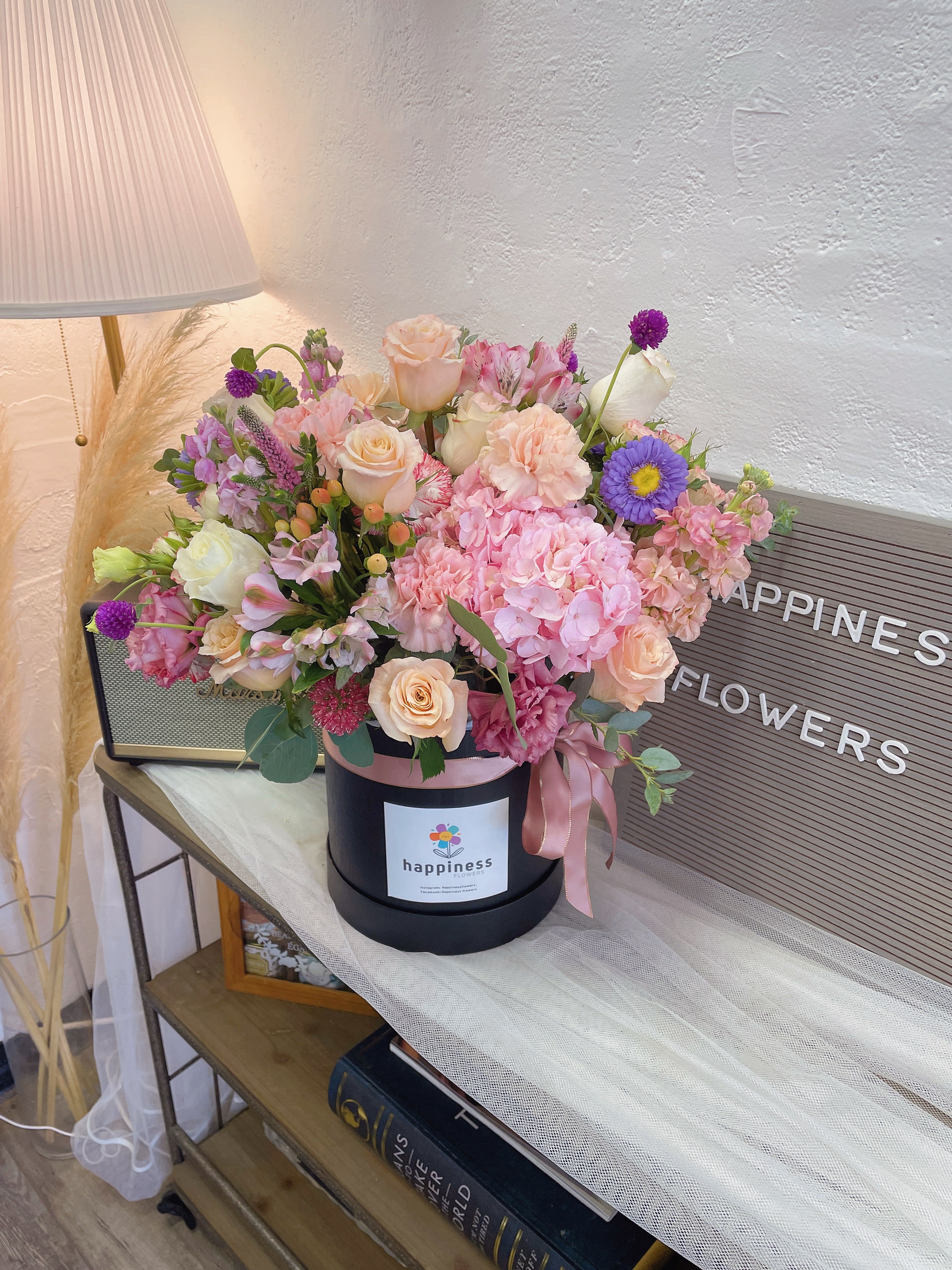Pink and peach flower arrangement in a black hat box