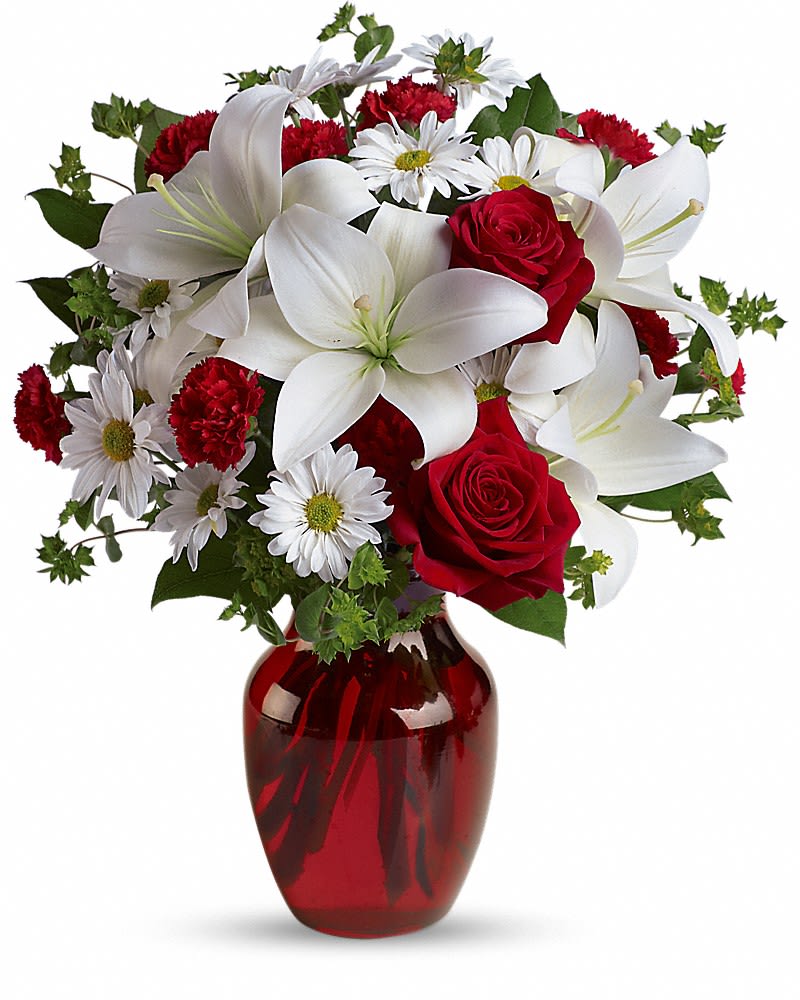 Bouquet of white lilies, red roses, and daisies in a red glass vase