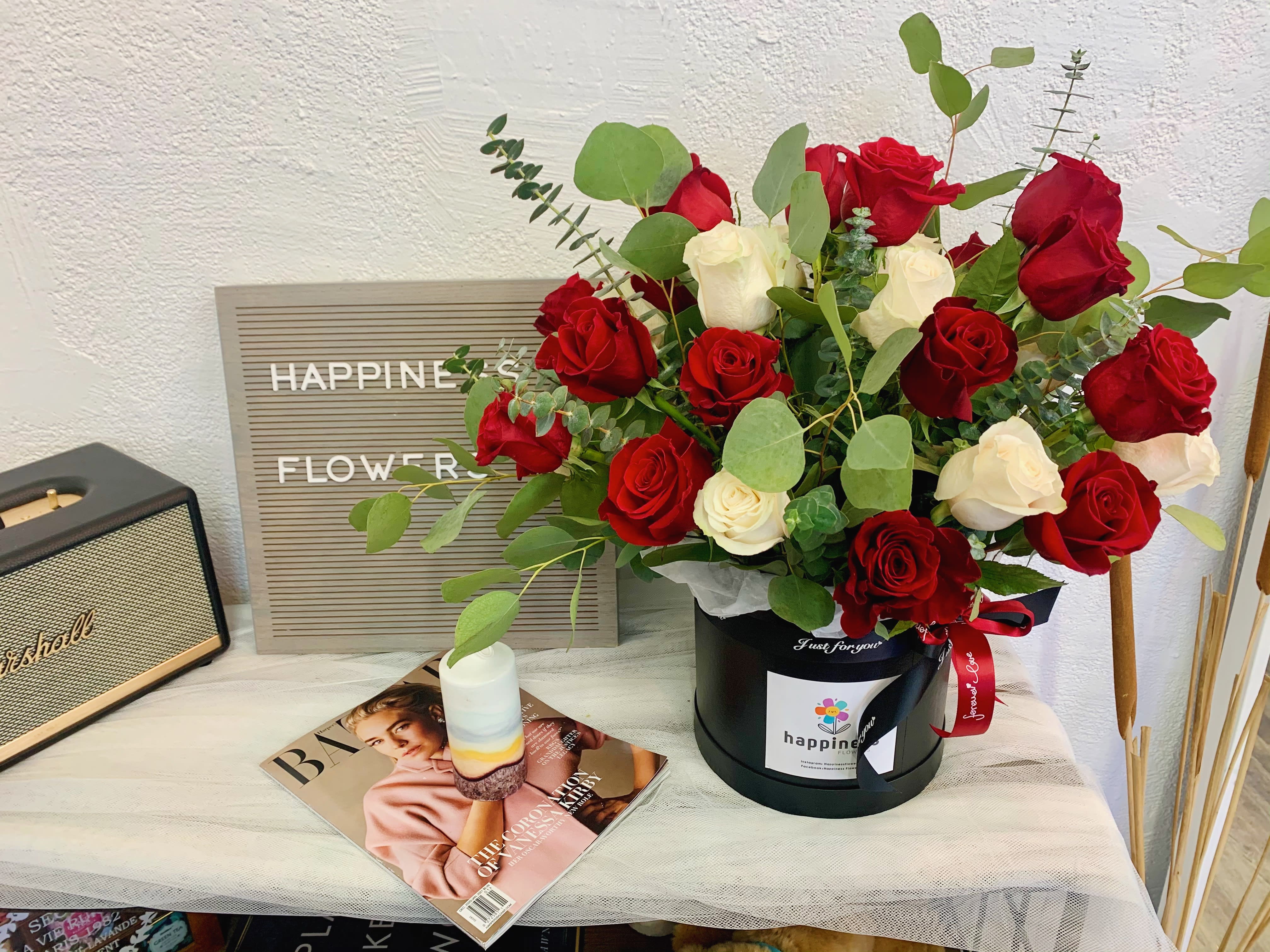 Red and white roses in a black hatbox with eucalyptus