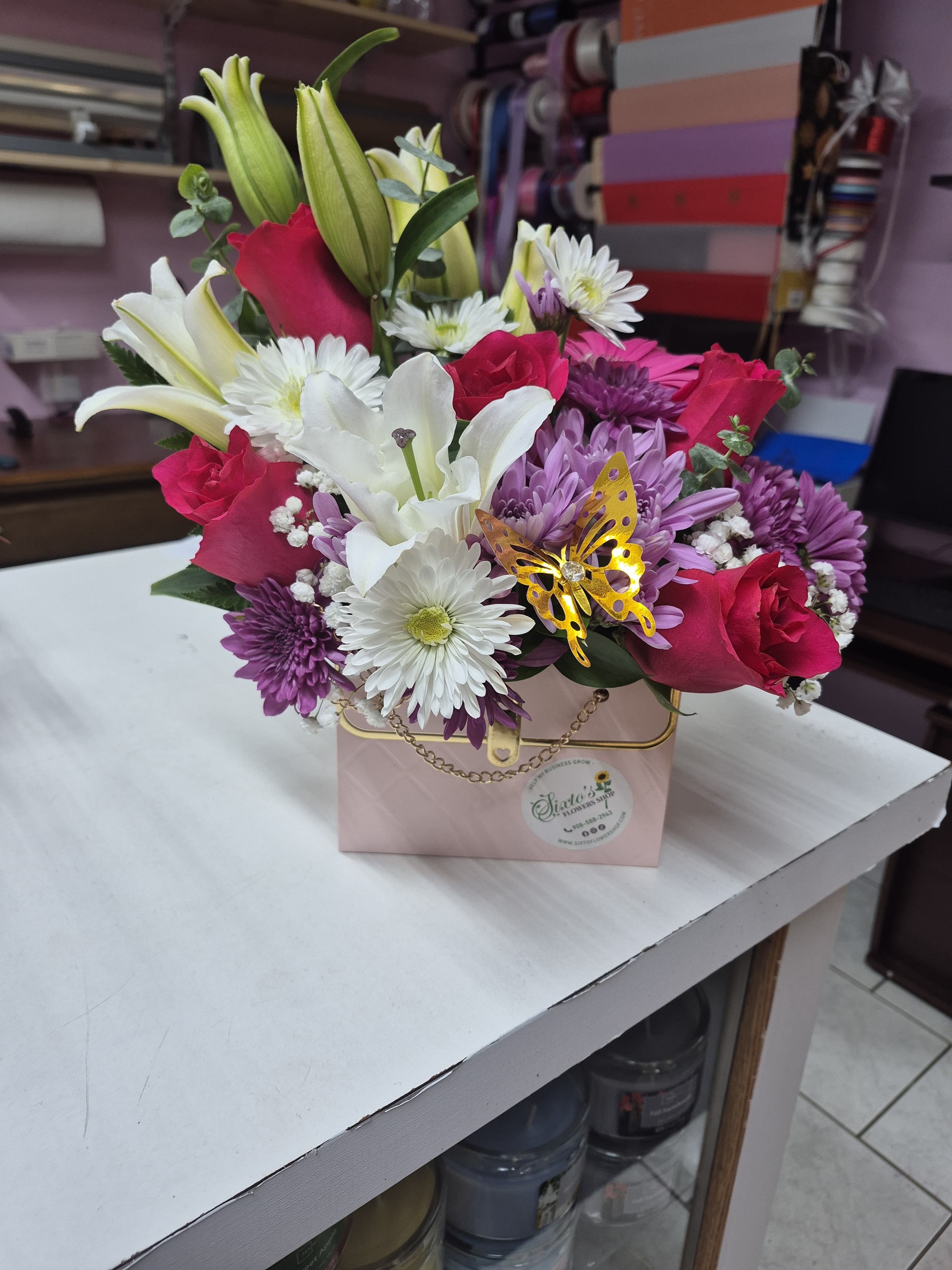 Mixed bouquet with lilies, roses, and daisies in a pink box