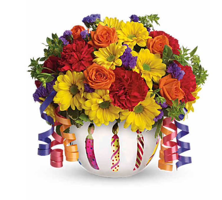 Colorful bouquet of roses, daisies, and carnations in a white vase with curling ribbons