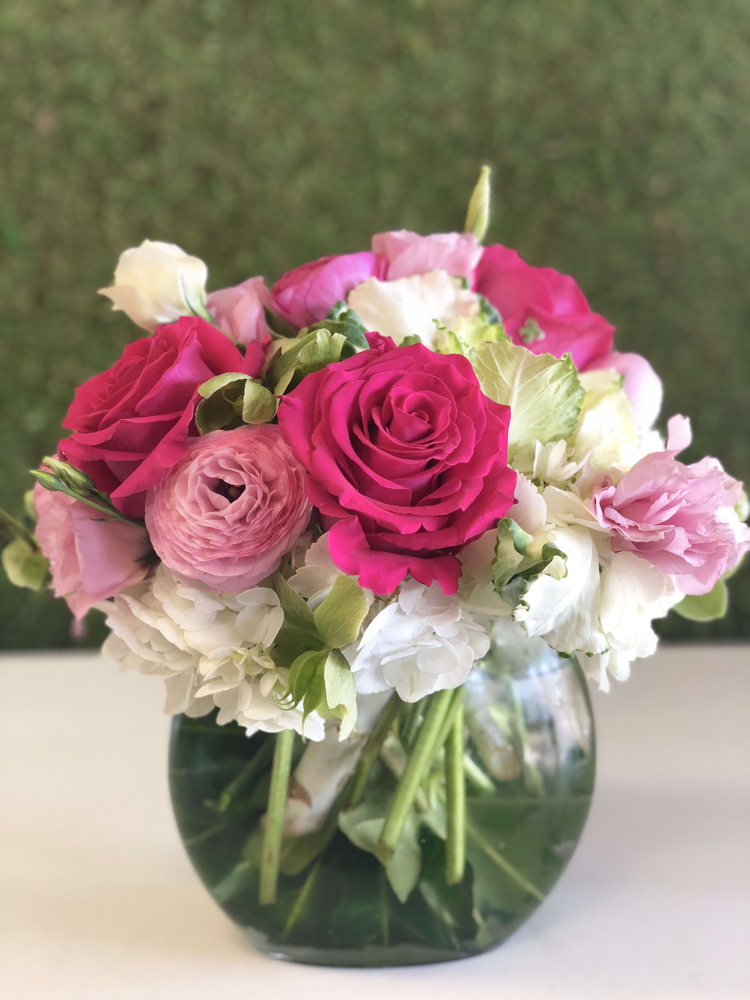 Pink and white bouquet of roses, ranunculus, and hydrangeas in a glass vase