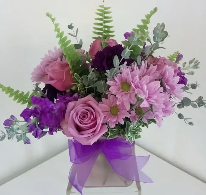 Pink and purple bouquet in a clear vase with a purple ribbon