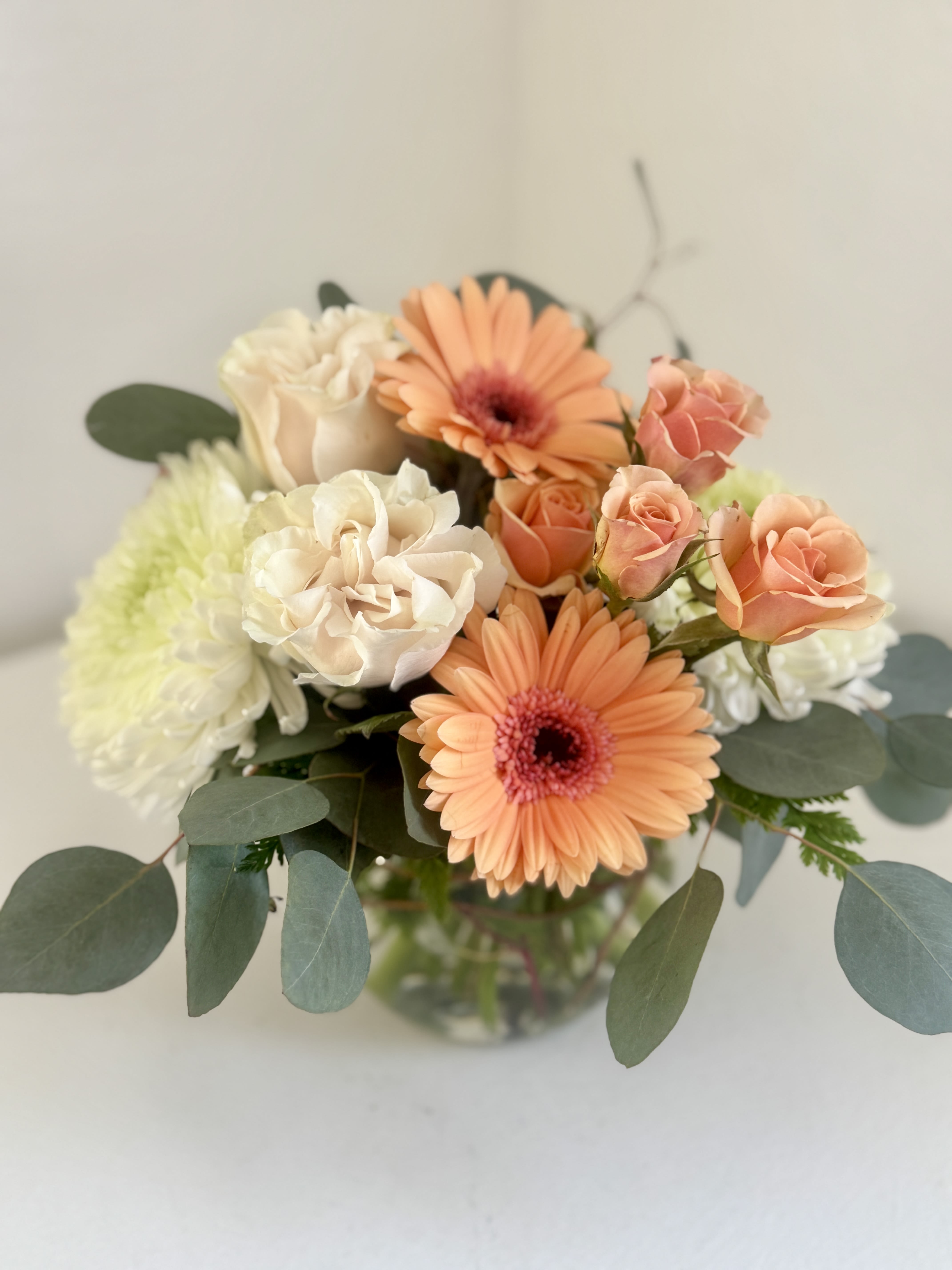 Peach gerberas and cream roses in a glass vase