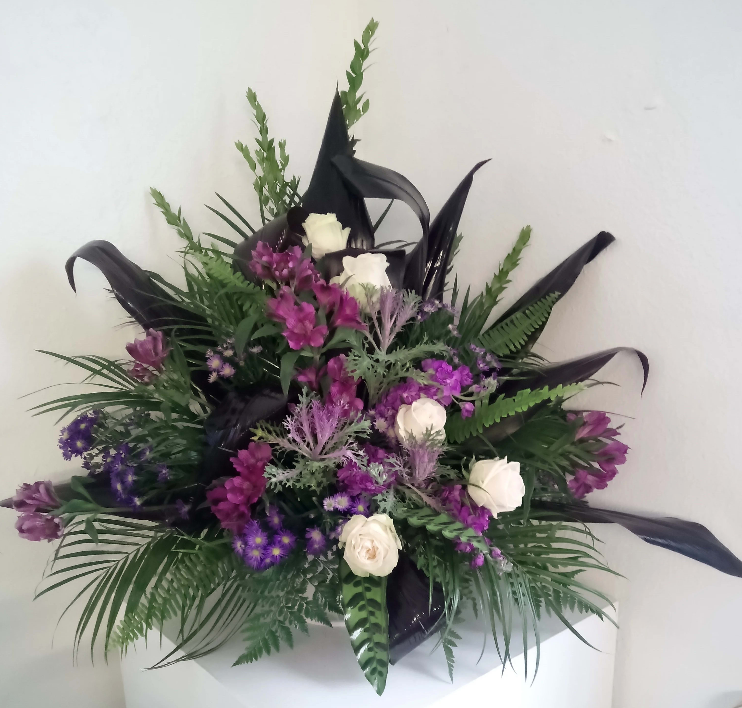 Purple and white floral arrangement with black ribbon accents